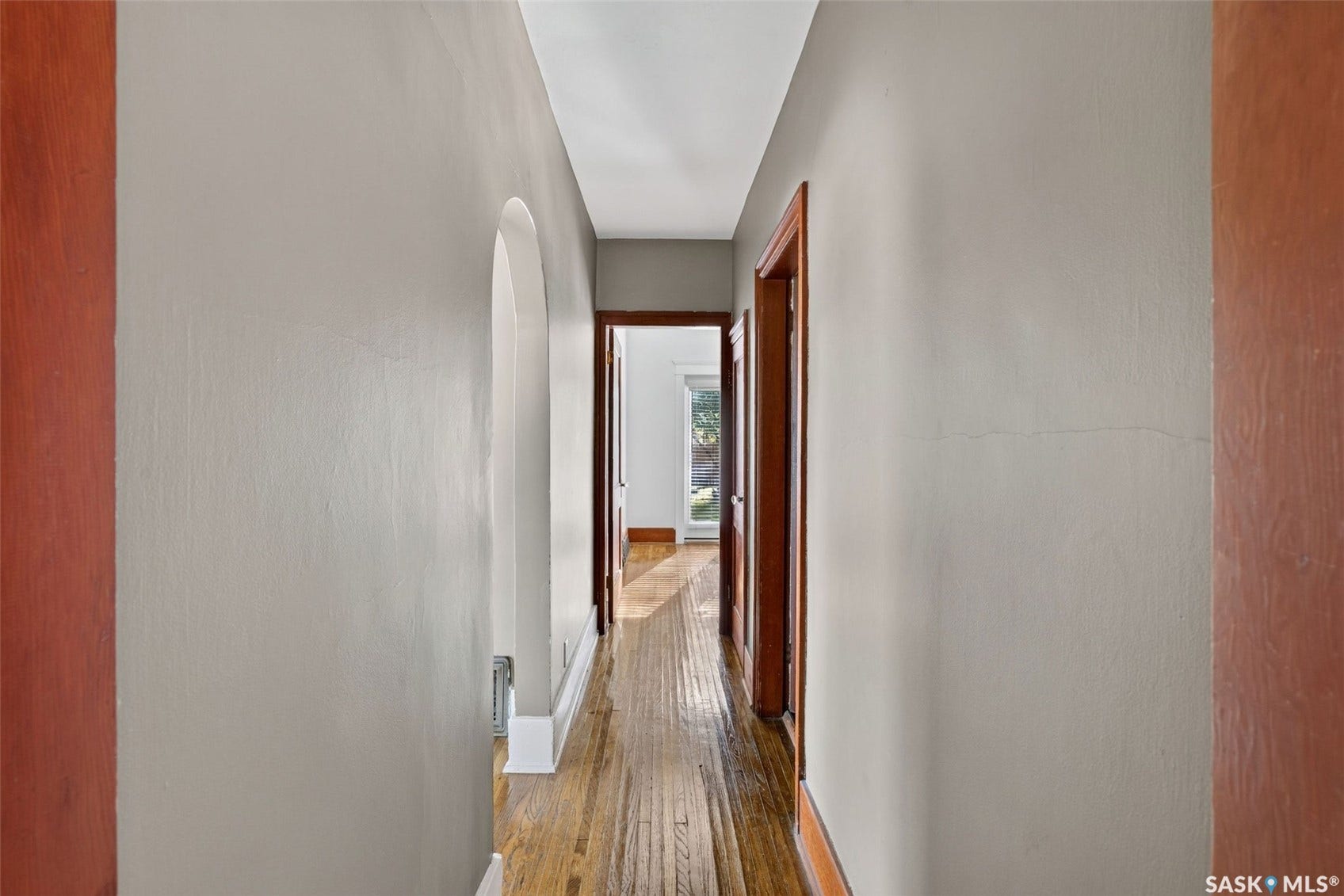 Hardwood flooring extending through the hallway, accented by an arched doorway and solid wood trim