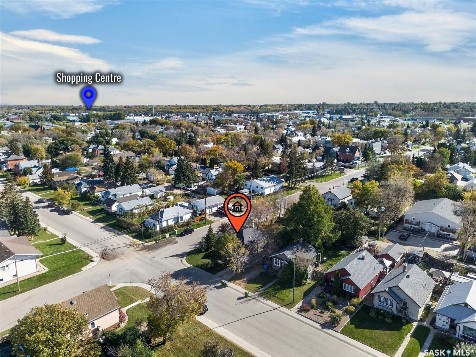 Aerial perspective of a residential neighborhood with a shopping center visible in the distance