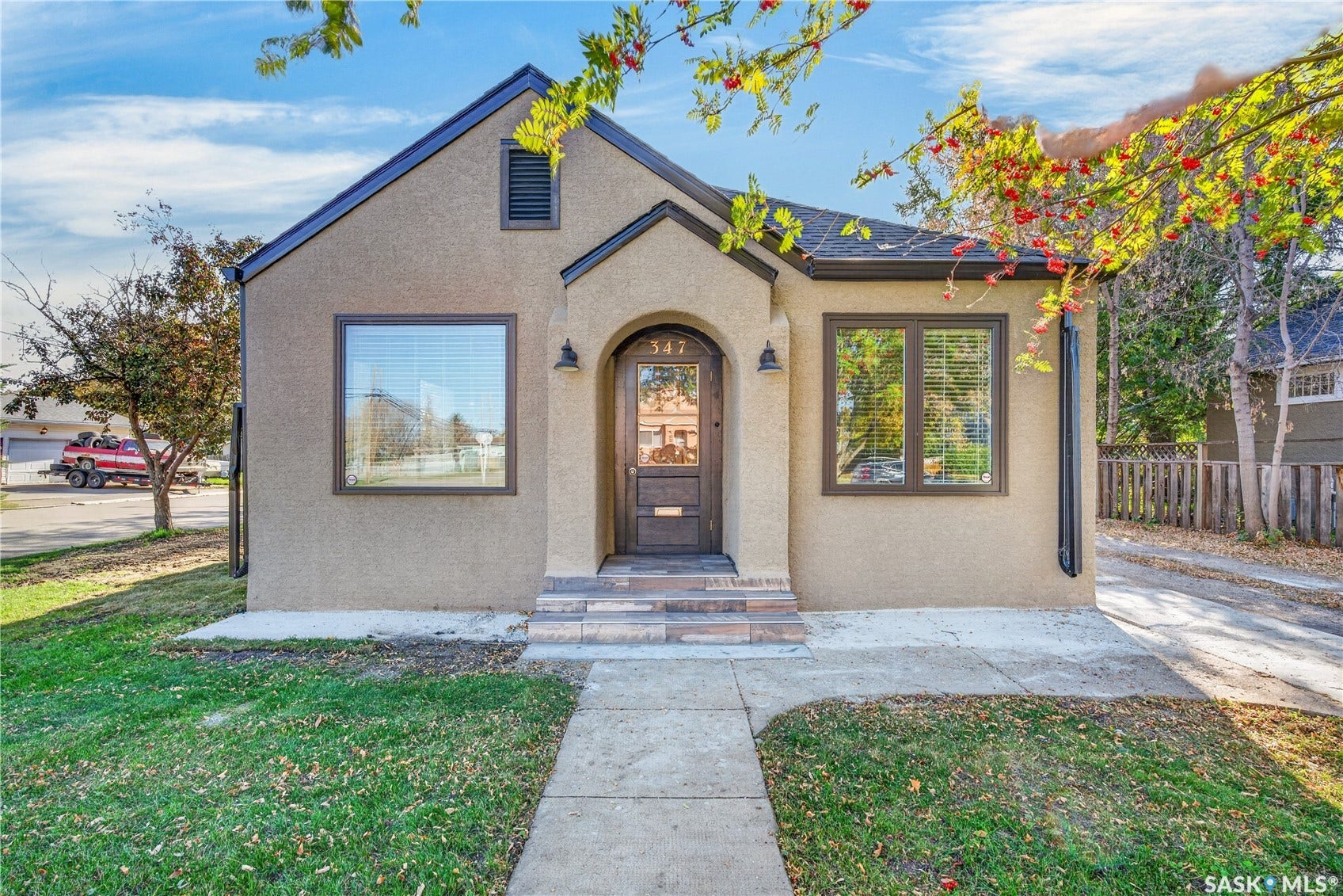 Stucco exterior with a peaked roof, arched entry, and dark-framed windows