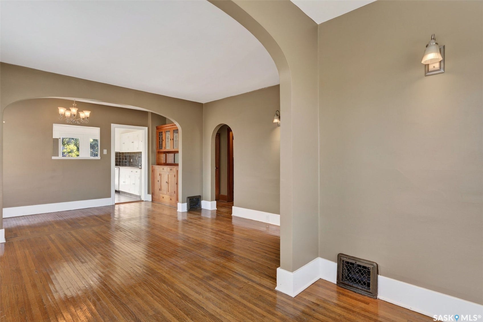Wood-finish flooring throughout, featuring arched doorways and built-in wall sconces