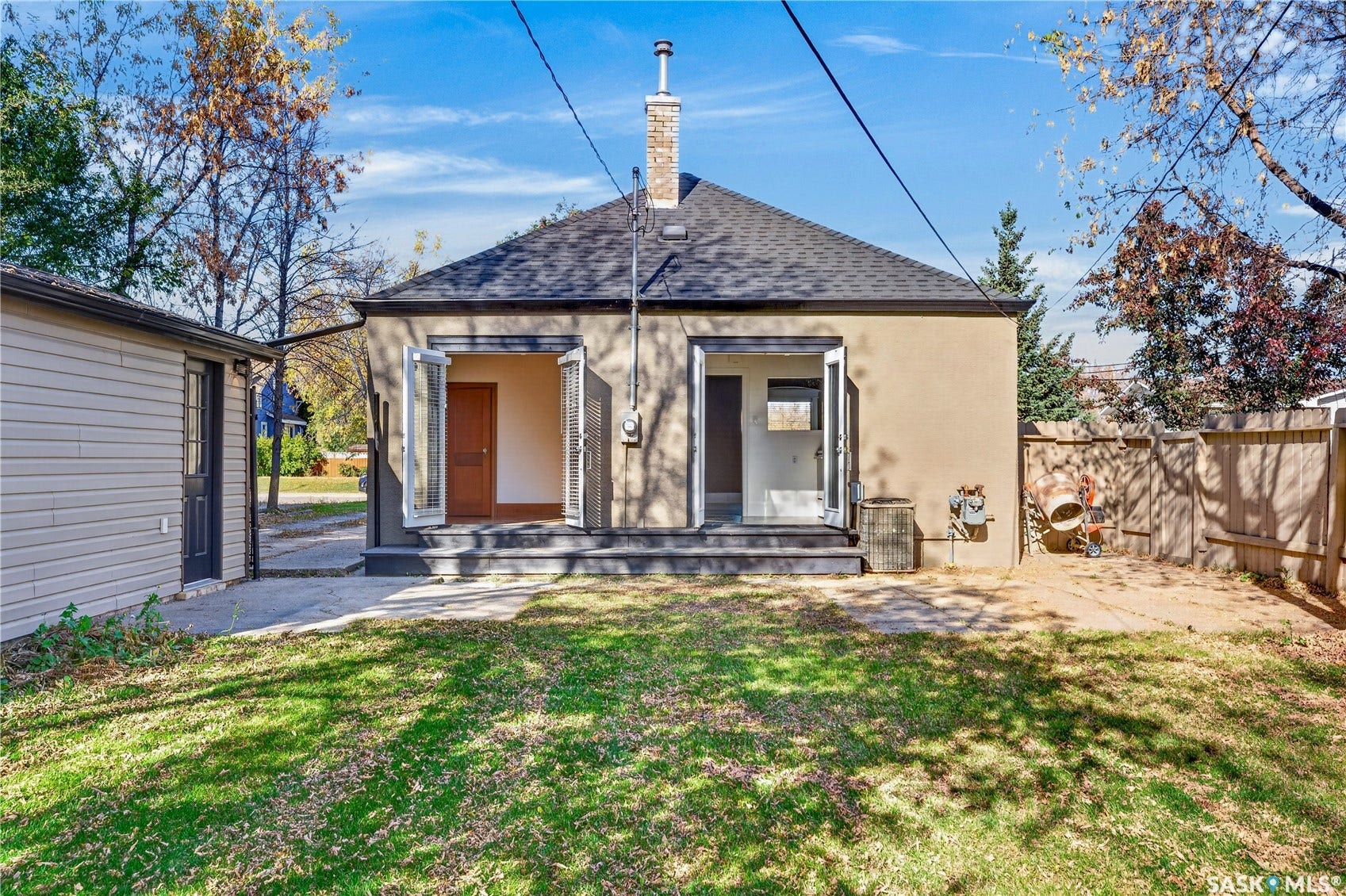 Stucco exterior with a pitched shingle roof and a brick chimney
