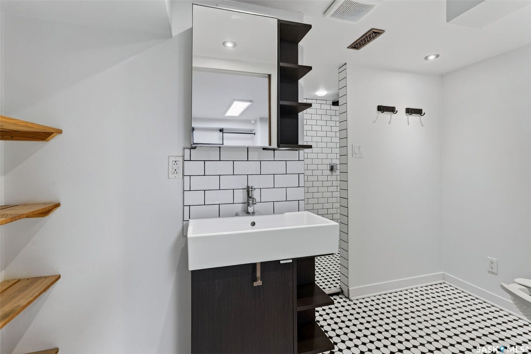 Vanity with integrated sink, subway tile backsplash, and black and white mosaic floor tile