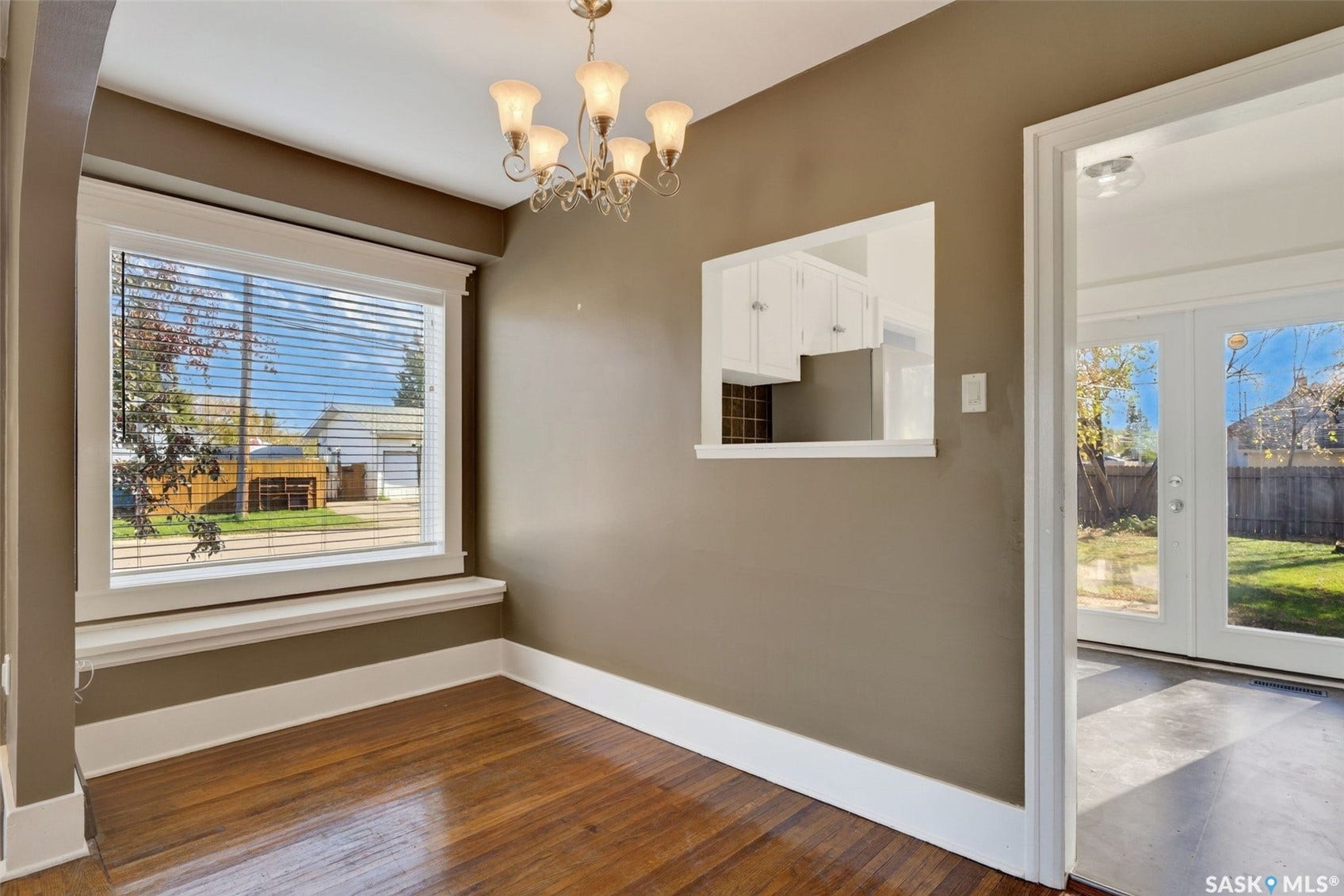 Wood-finish flooring, white trim, and a decorative chandelier