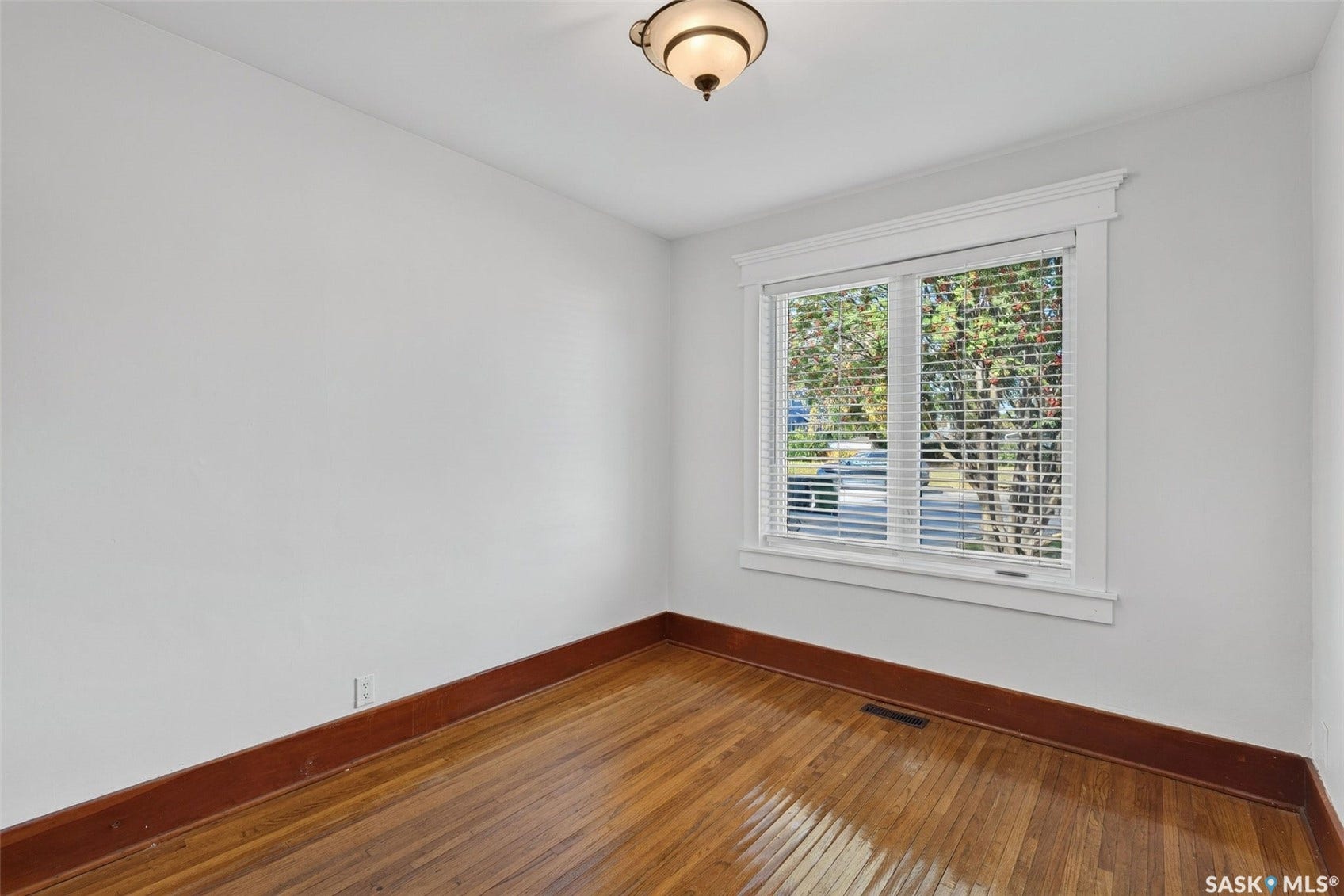 Hardwood flooring, white walls, and a single window with blinds