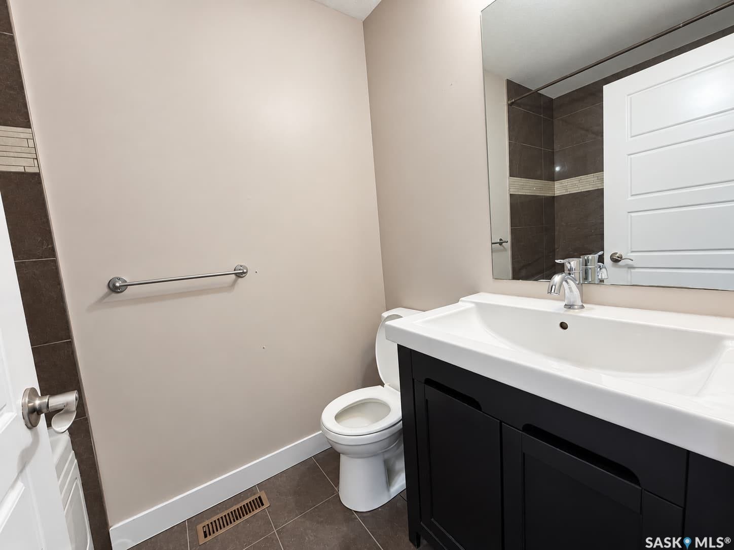 Vanity with integrated sink, wall-mounted mirror, and tile flooring
