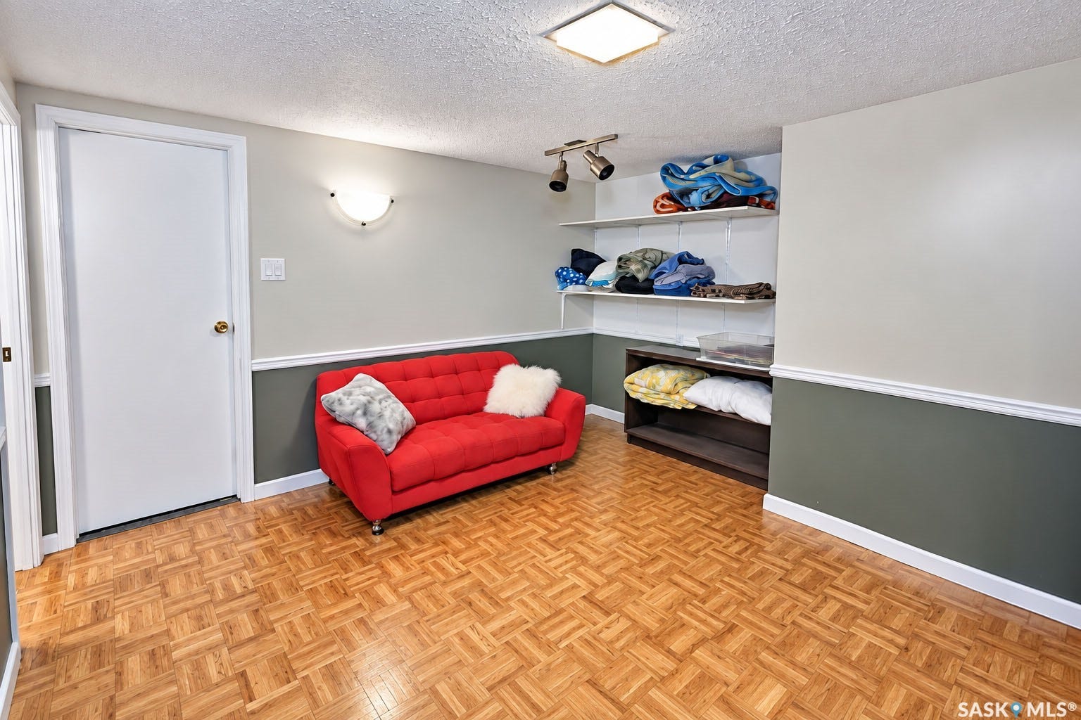 Parquet flooring, two-tone wall treatment, built-in shelving, track lighting, and a flush-mount ceiling light