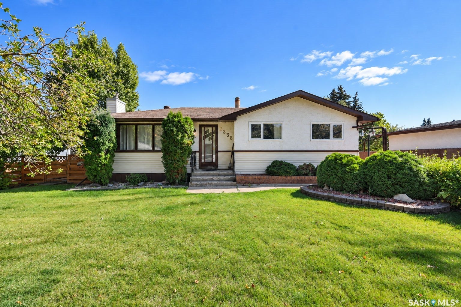 Single-story residence featuring a white and beige exterior, a dark brown roof, and multiple windows