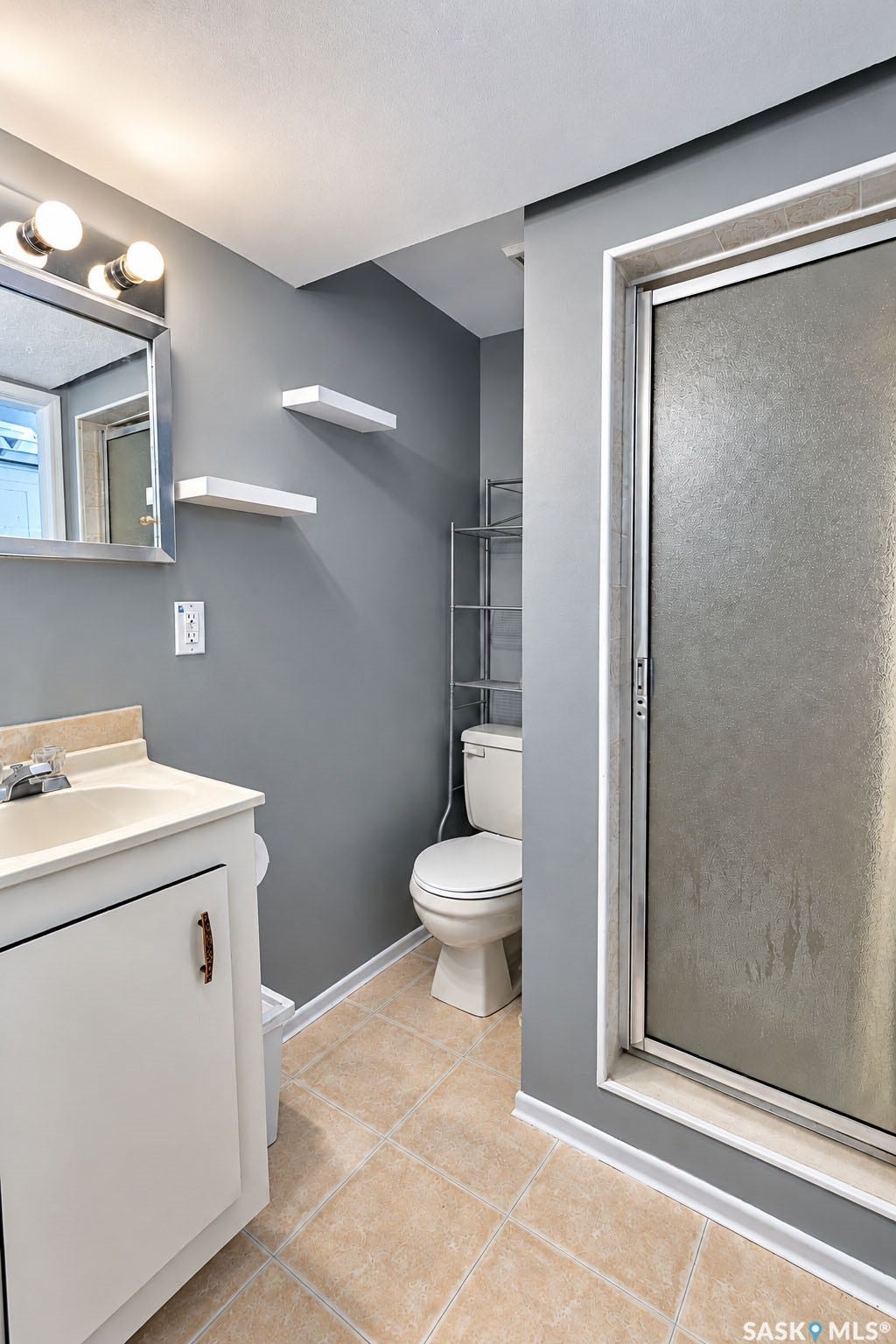 Full bathroom featuring a single vanity, frameless mirror, and a shower with a frosted glass enclosure