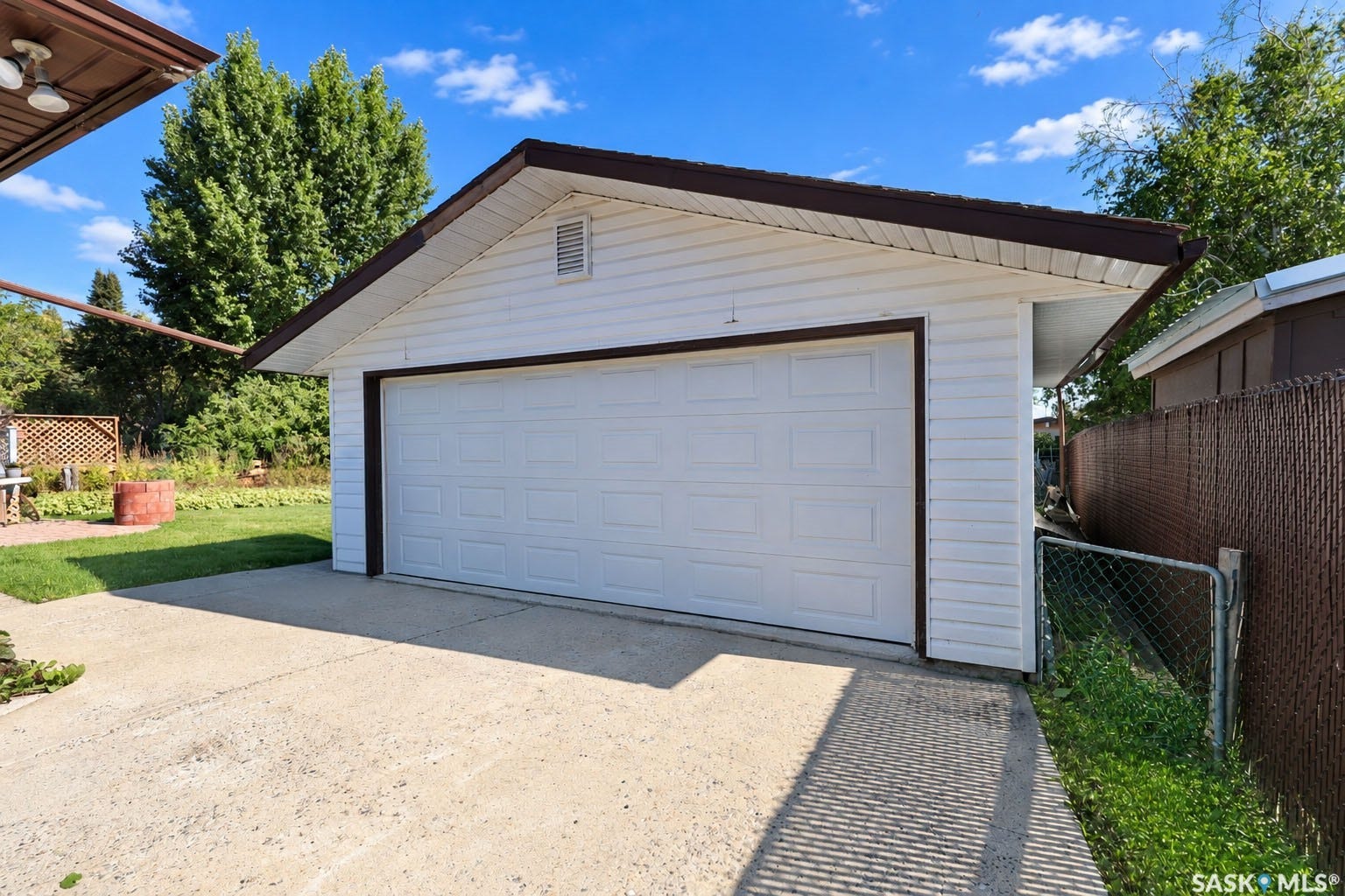 Detached garage with white siding, a single overhead door, and a concrete driveway