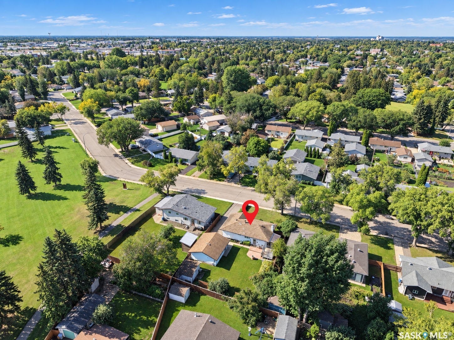 Residential neighborhood setting with mature trees and a nearby green space