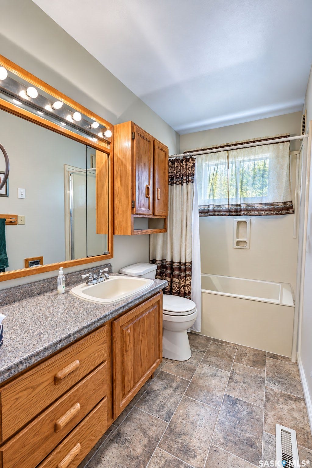 Bathroom with wood-finish vanity, integrated sink, and a combination tub/shower