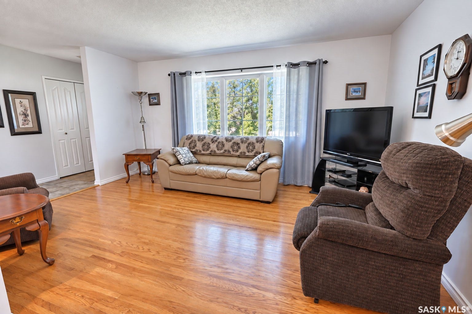 Hardwood-style flooring throughout, with a large window offering natural light, and a white bi-fold closet door