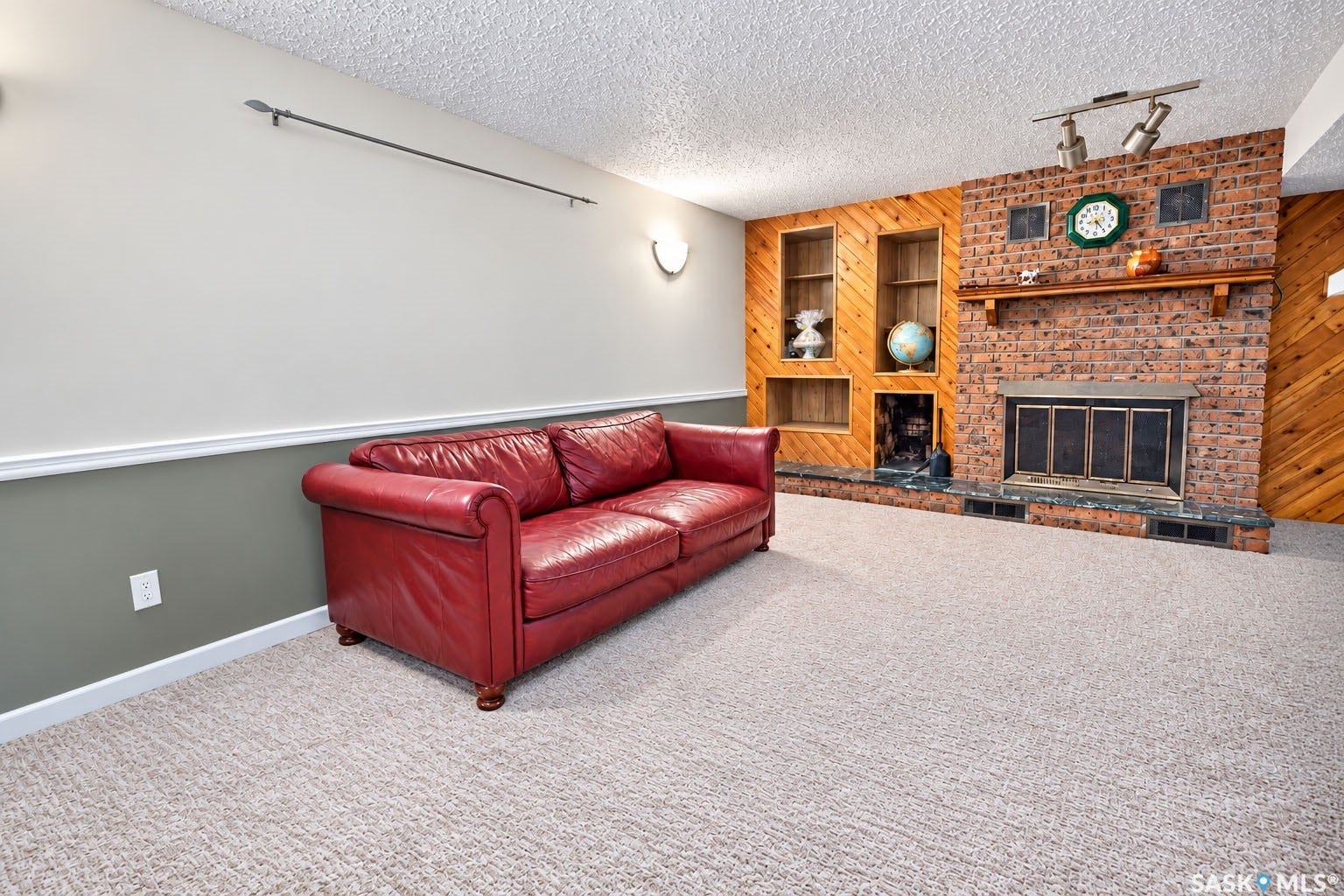 Brick fireplace with a wood mantel and built-in shelving, complemented by wood-paneled walls