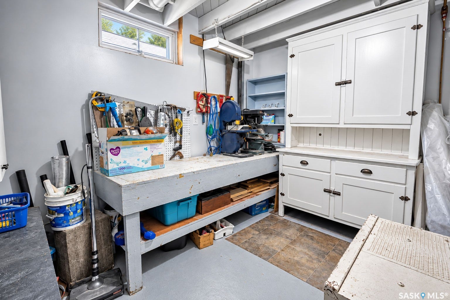 Dedicated workspace featuring a built-in workbench, pegboard organization, and a white storage cabinet