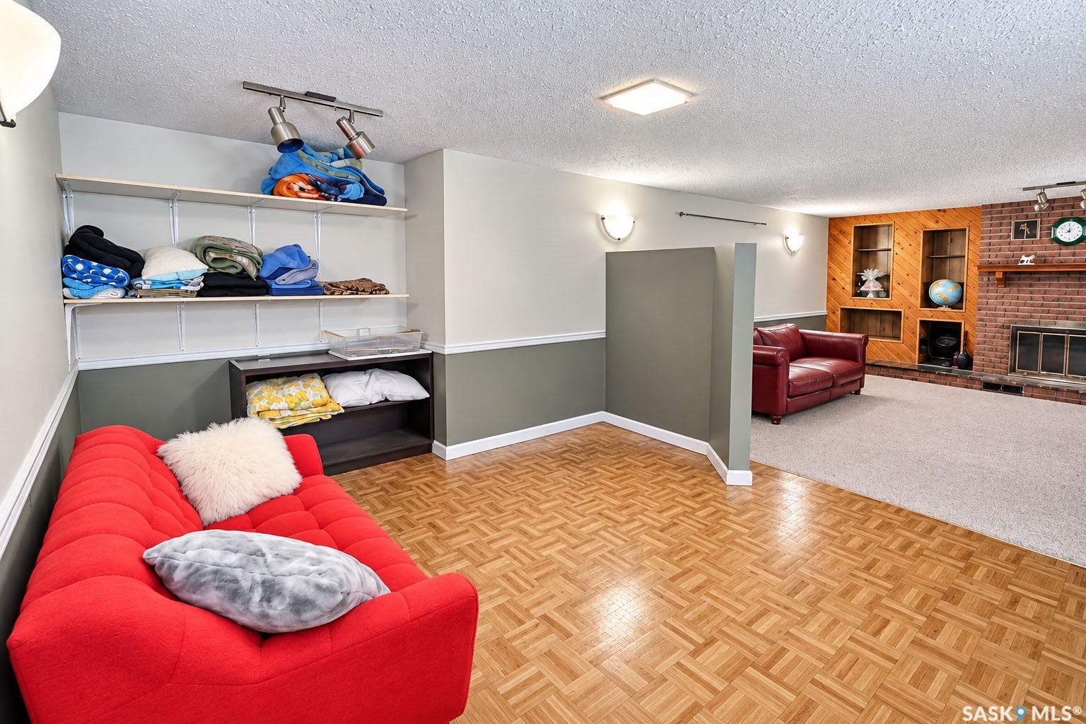 Parquet wood-finish flooring, two-tone wall treatment, built-in shelving, brick fireplace with mantel, and recessed lighting