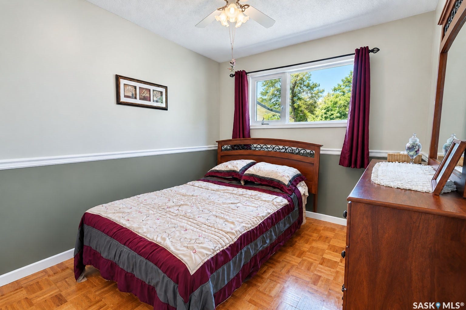 Parquet wood-finish flooring, two-tone painted walls, and a window with a treed backdrop