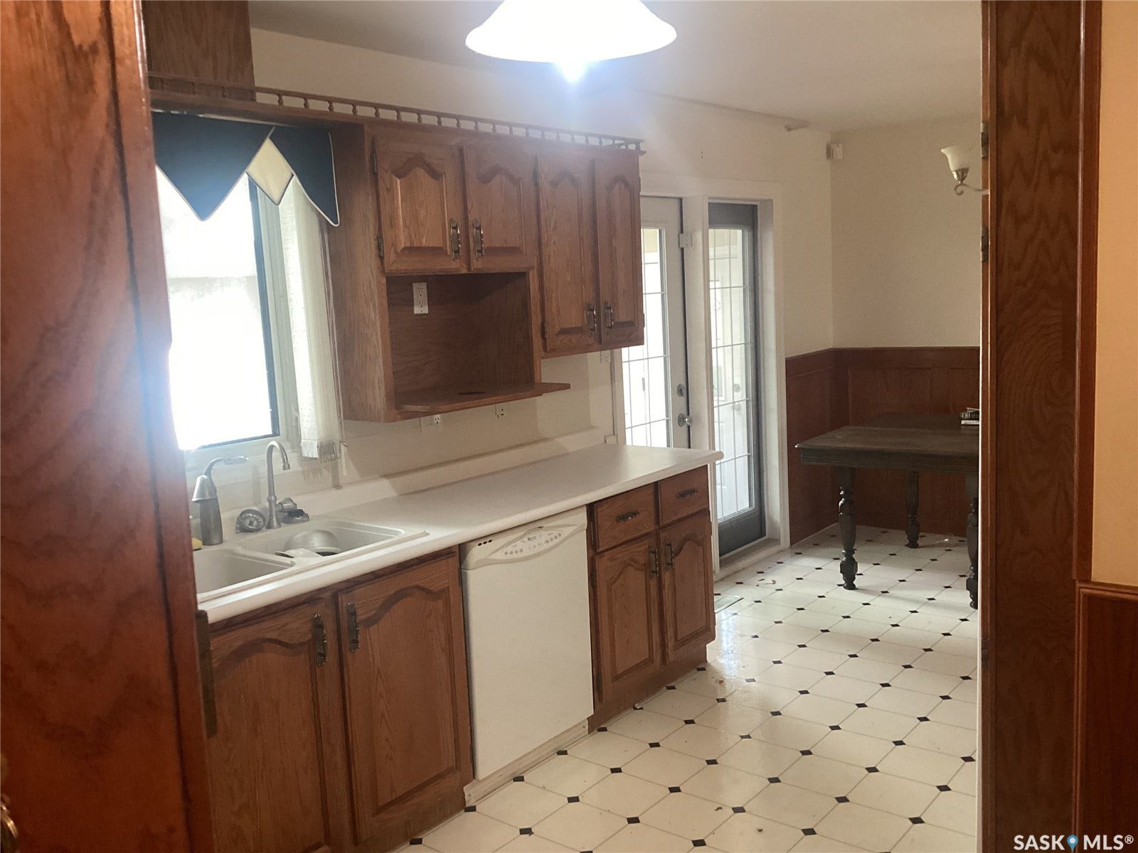 Kitchen featuring wood cabinetry, a double basin sink, white countertops, and checkerboard floor tiling