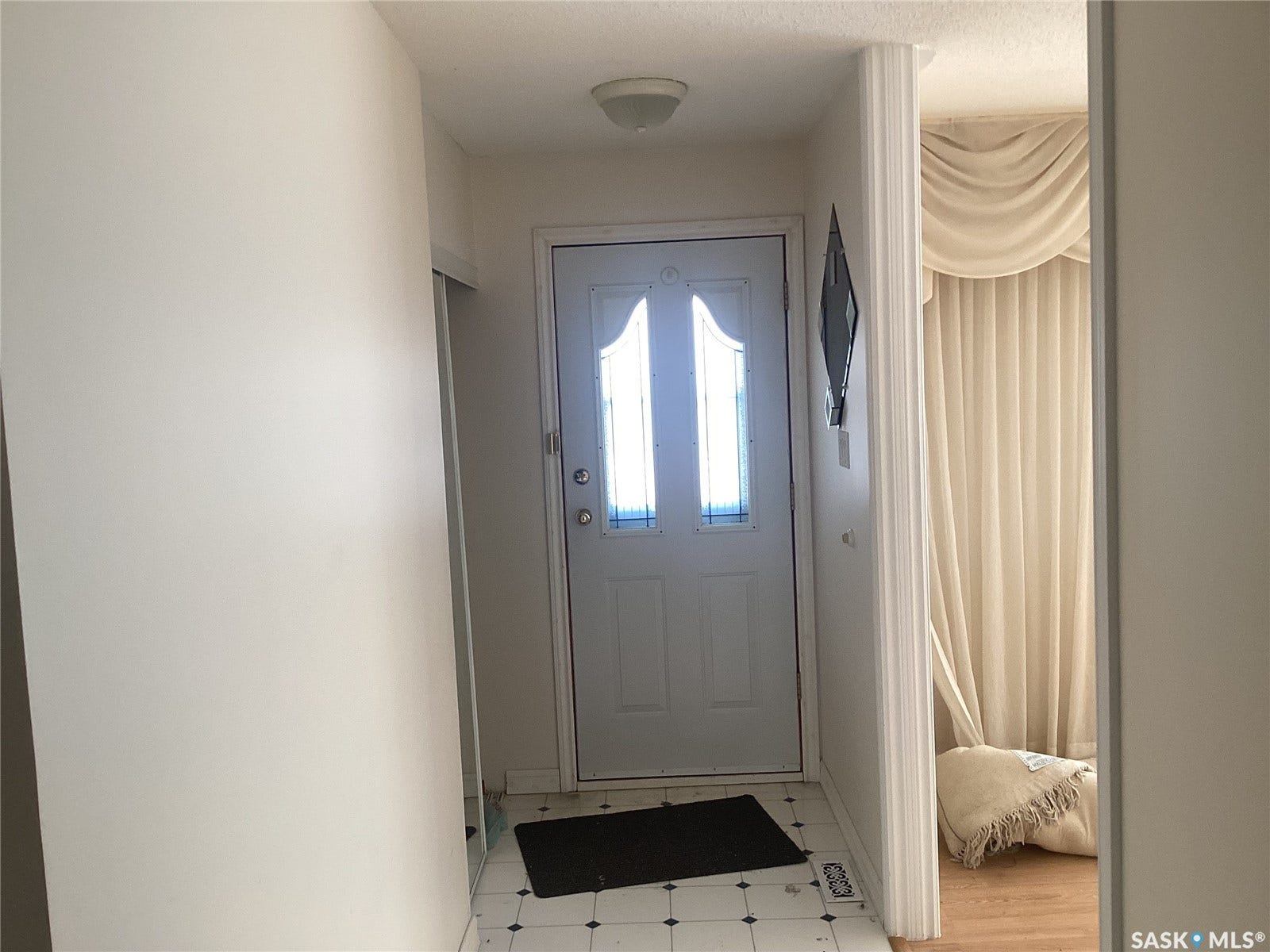 Entryway with a paneled door featuring decorative glass inserts, ceramic tile flooring, and a flush-mount ceiling light fixture