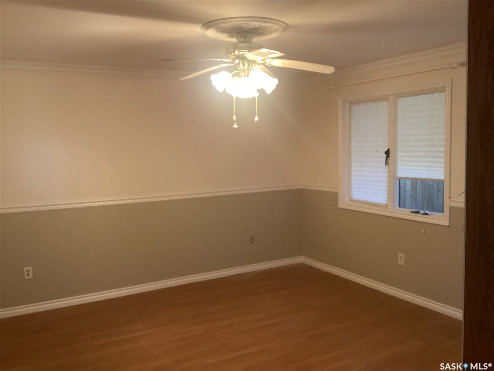 Wood-finish flooring, ceiling fan with light fixture, decorative crown molding, and chair rail detailing