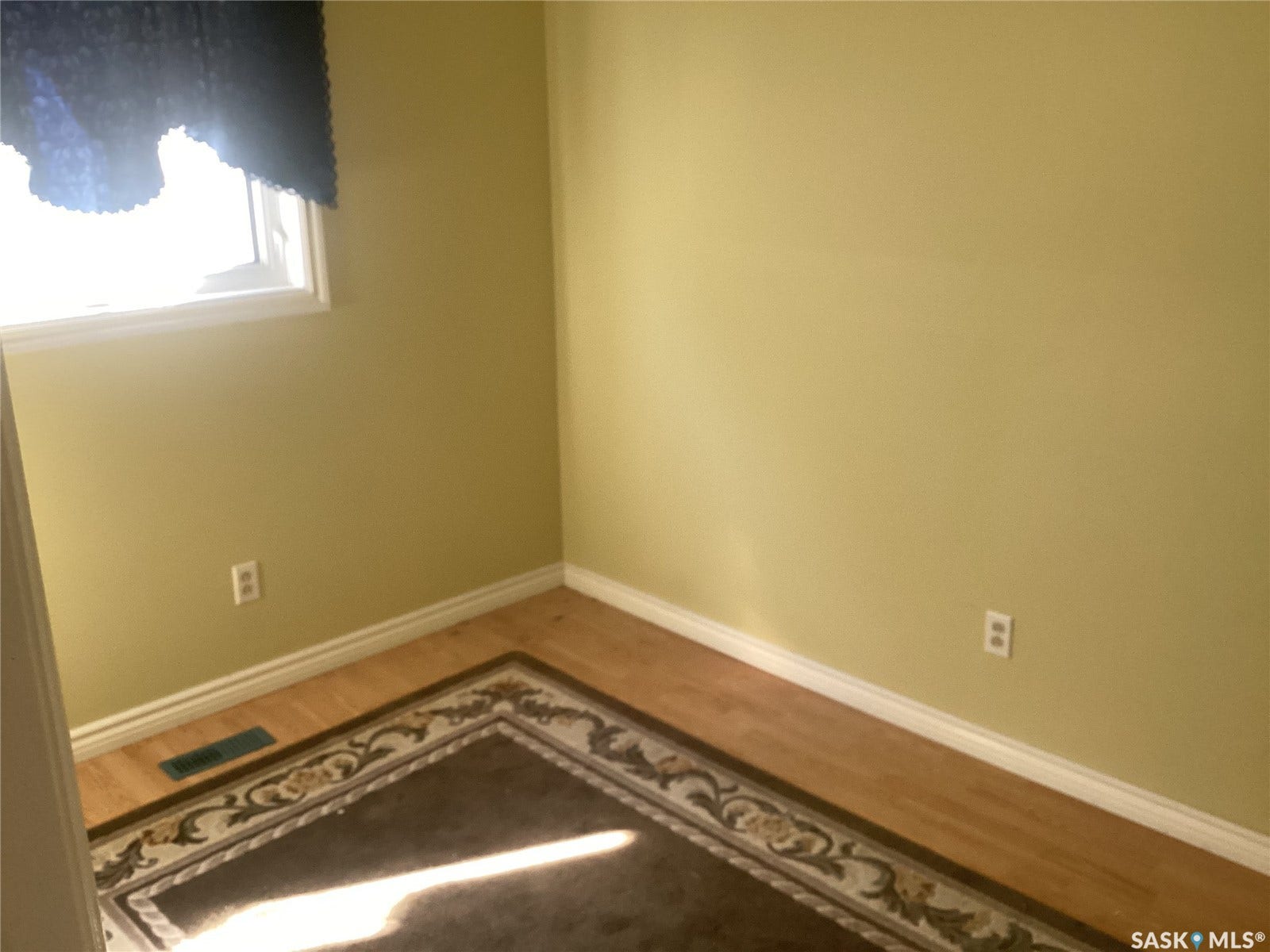 Wood-finish flooring with white trim and a single window