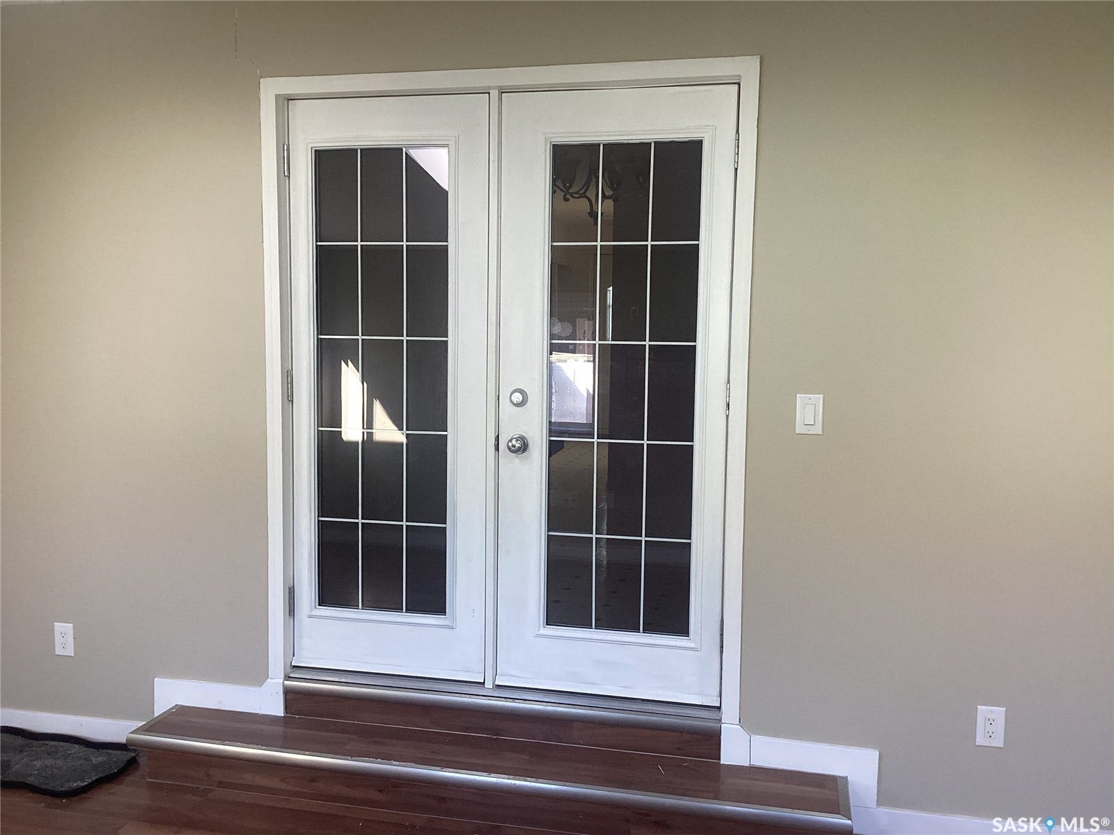 White French doors with gridded glass panels, wood-finish flooring, and light neutral wall paint