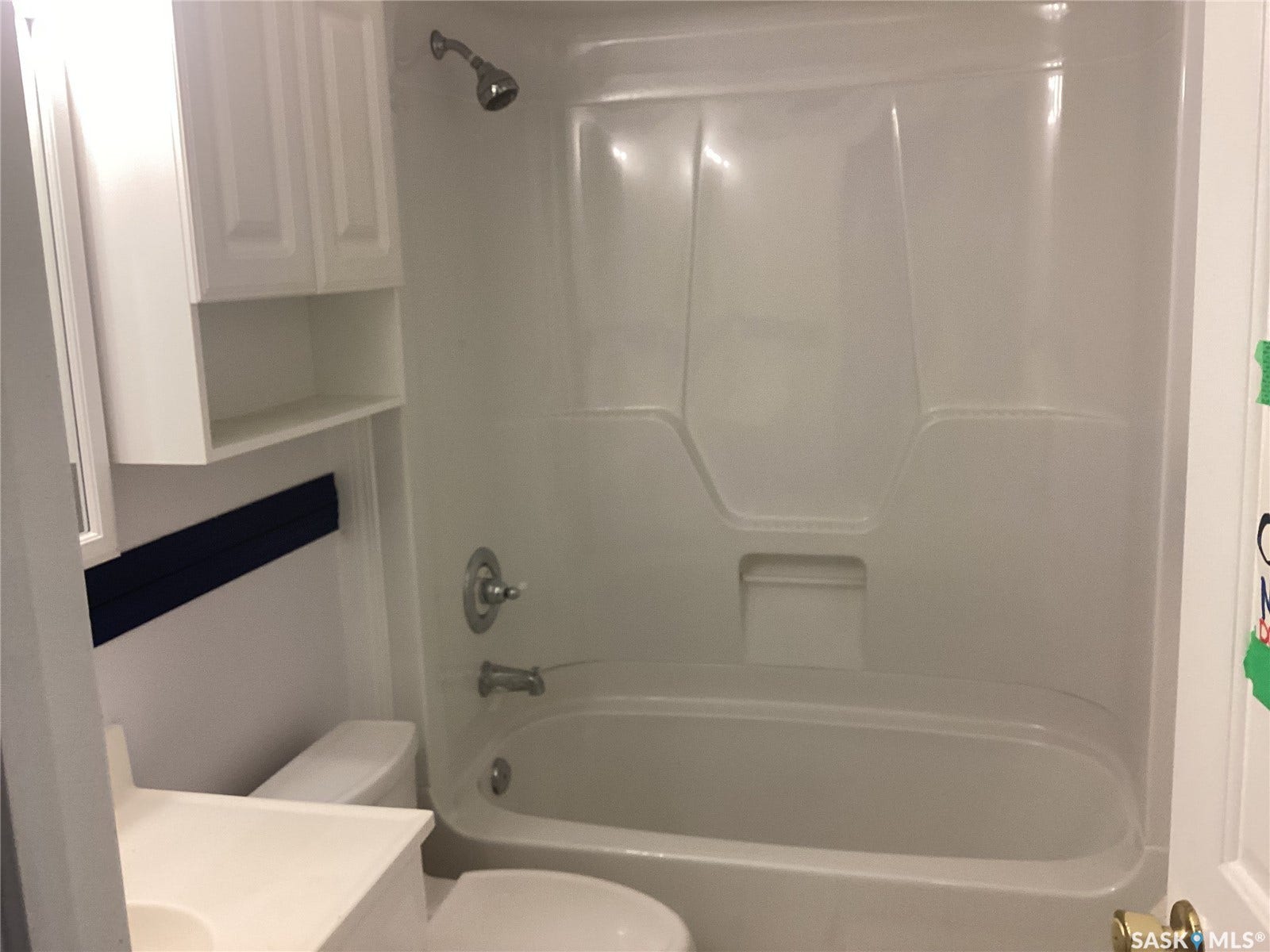 White fiberglass tub and shower combination with a showerhead and tub filler
