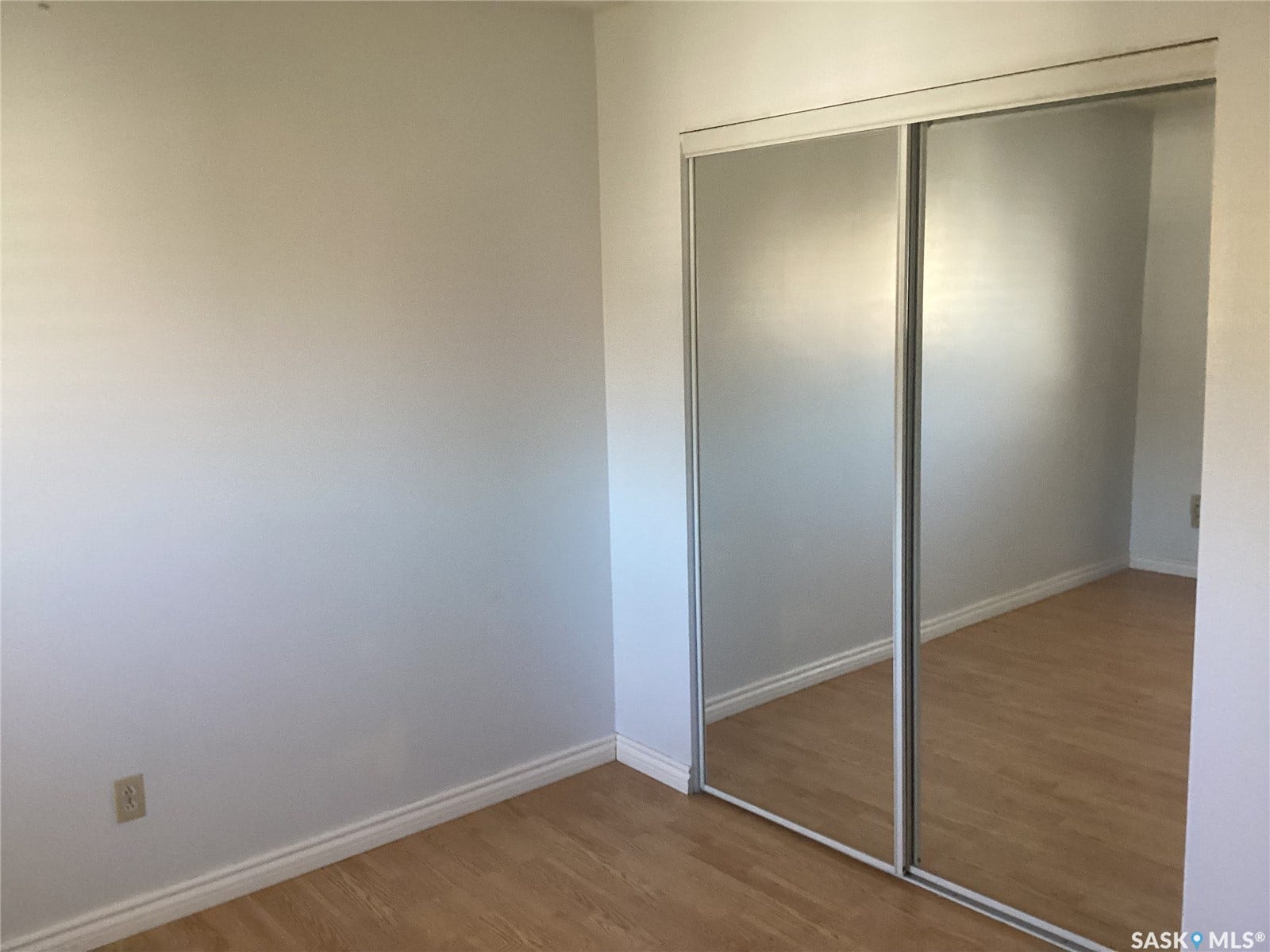 Mirrored sliding closet doors, wood-finish flooring, and light-toned walls