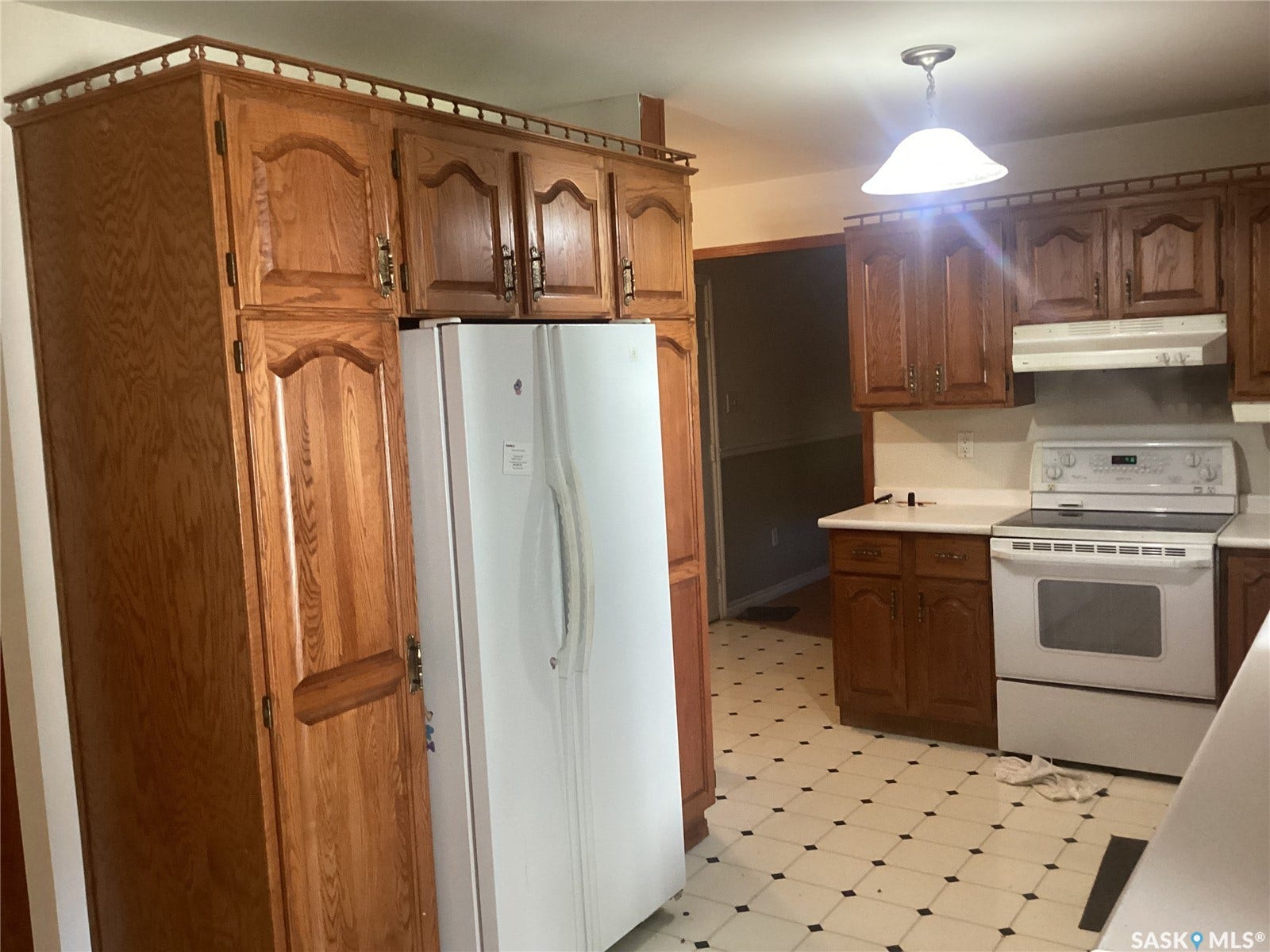 Kitchen featuring wood-finish cabinetry, white countertops, a white electric range, and checkered tile flooring