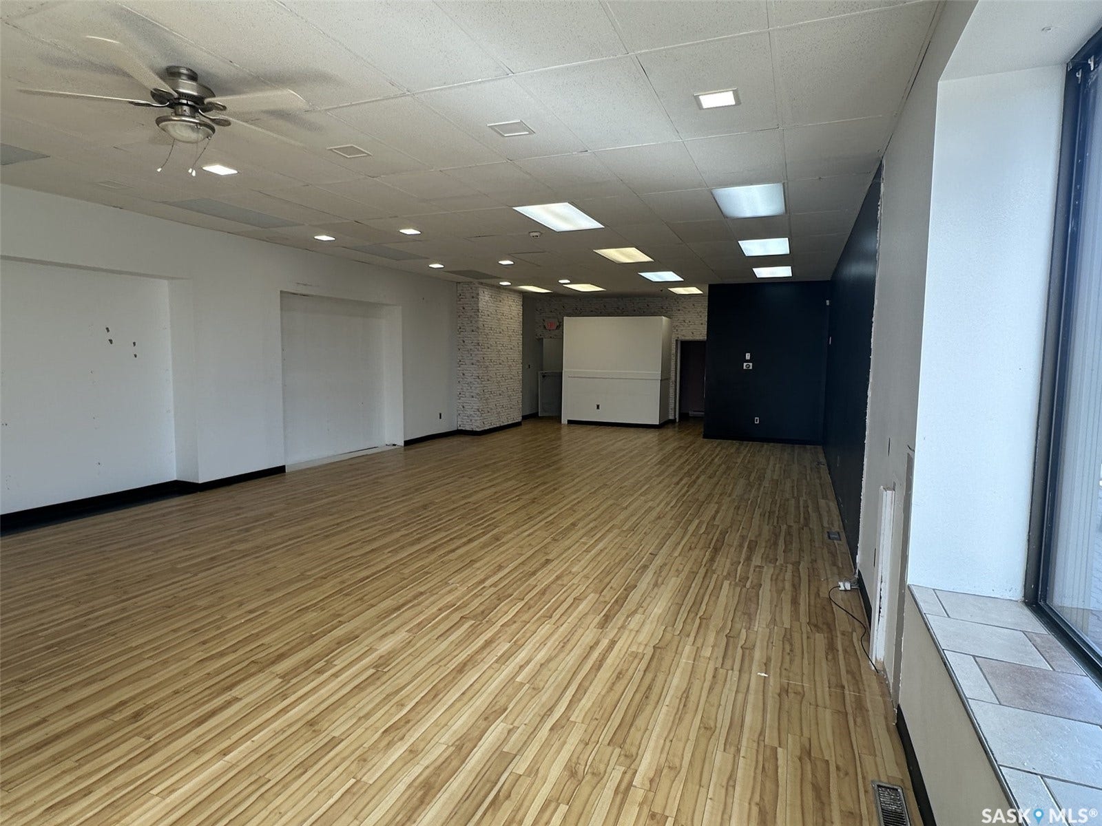 Wood-finish flooring, recessed lighting, ceiling fan, large front-facing window, and a tiled window ledge