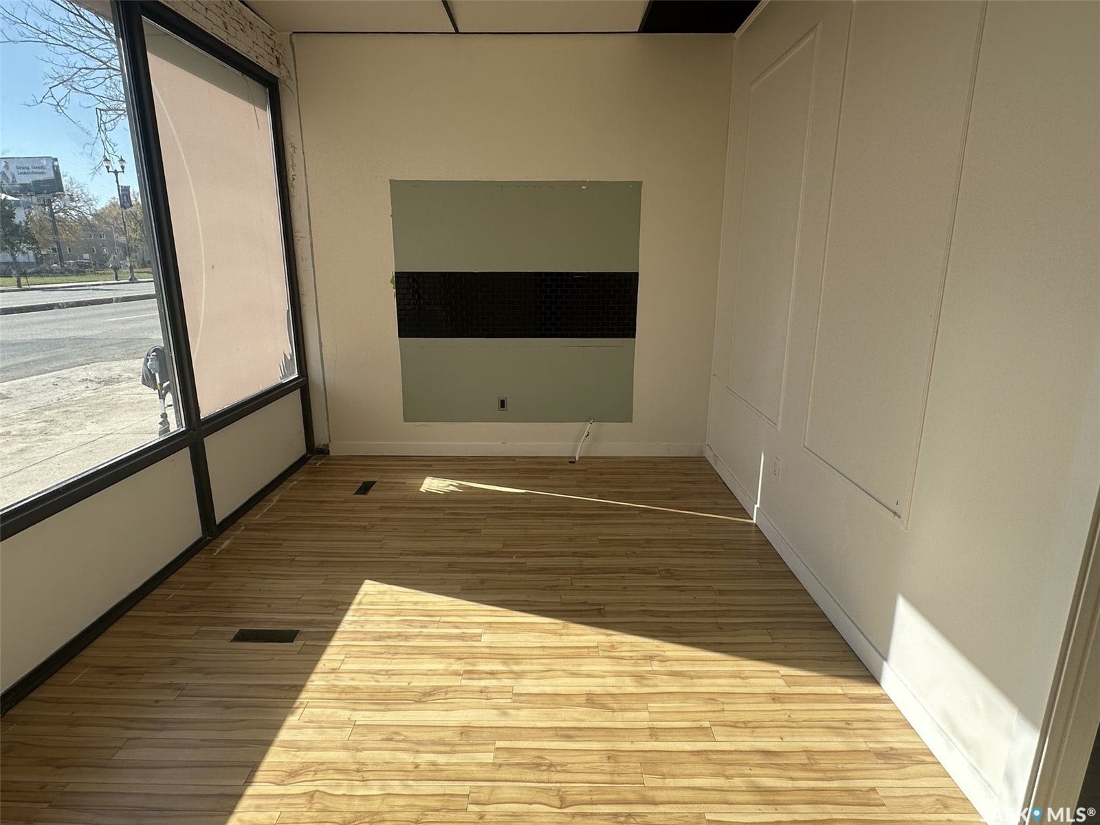 Expansive storefront window, wood-finish flooring, white paneling, and neutral wall tones