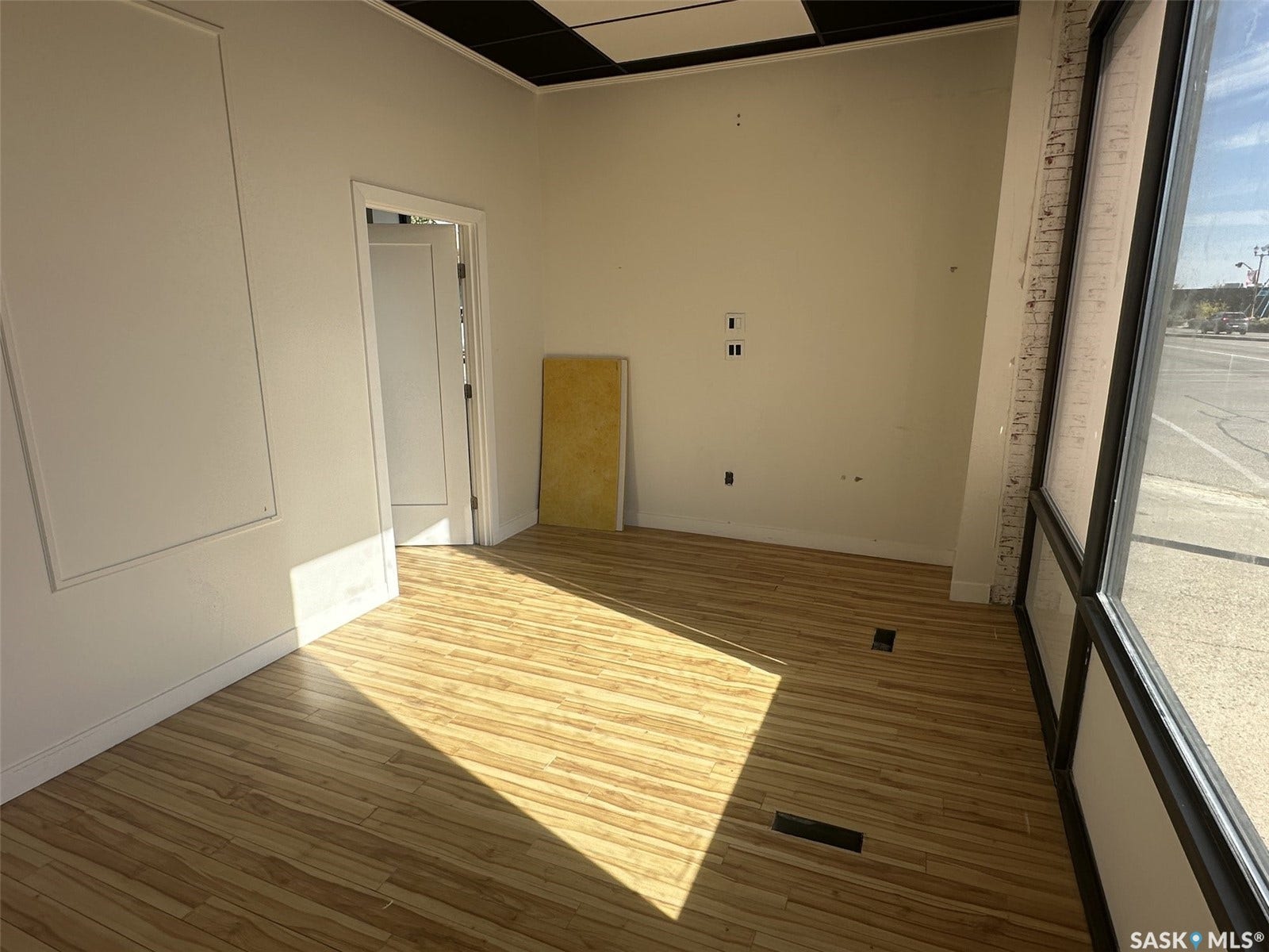 Wood-finish flooring, white walls, and a dropped ceiling with black tiles