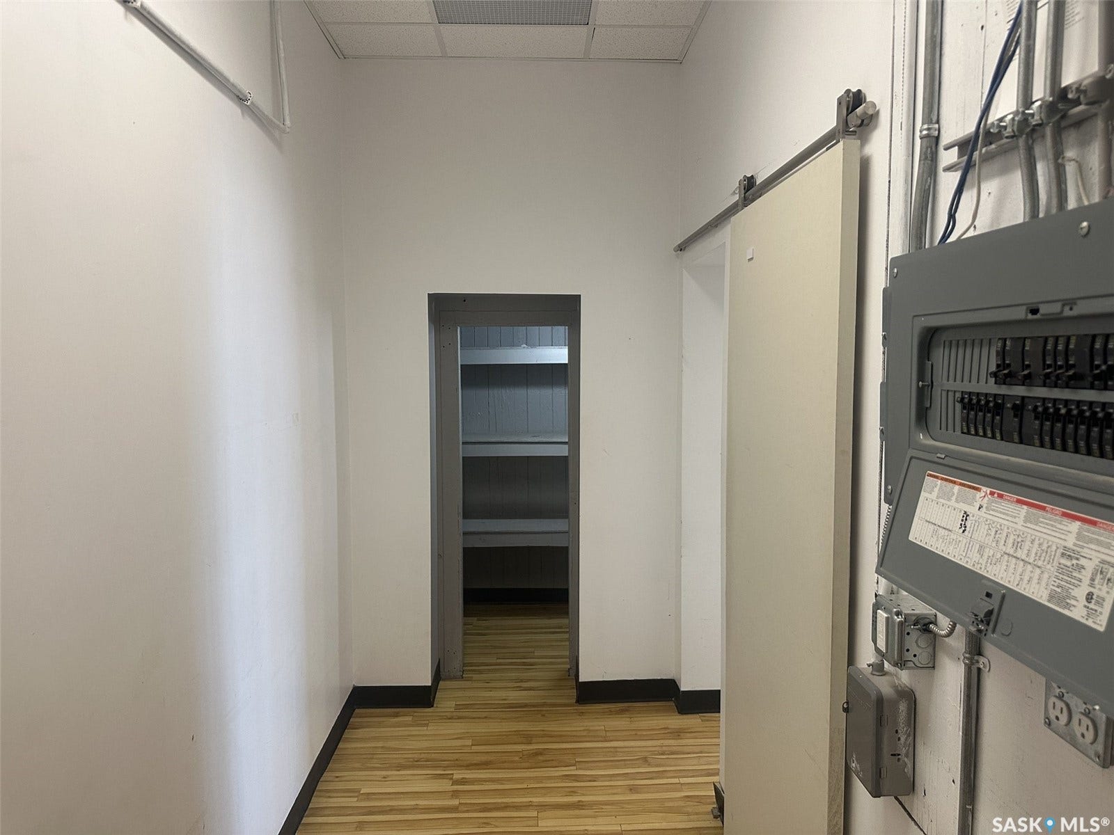 Wood-finish flooring with black trim, recessed ceiling lighting, and exposed conduit