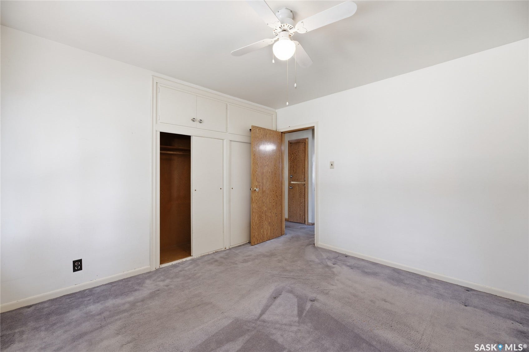 Integrated built-in cabinetry, sliding closet doors, ceiling fan, and light-toned walls