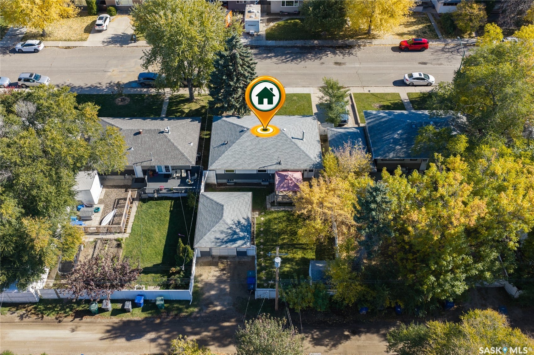 Expansive rear yard with a manicured lawn, established landscaping, and a multi-level deck