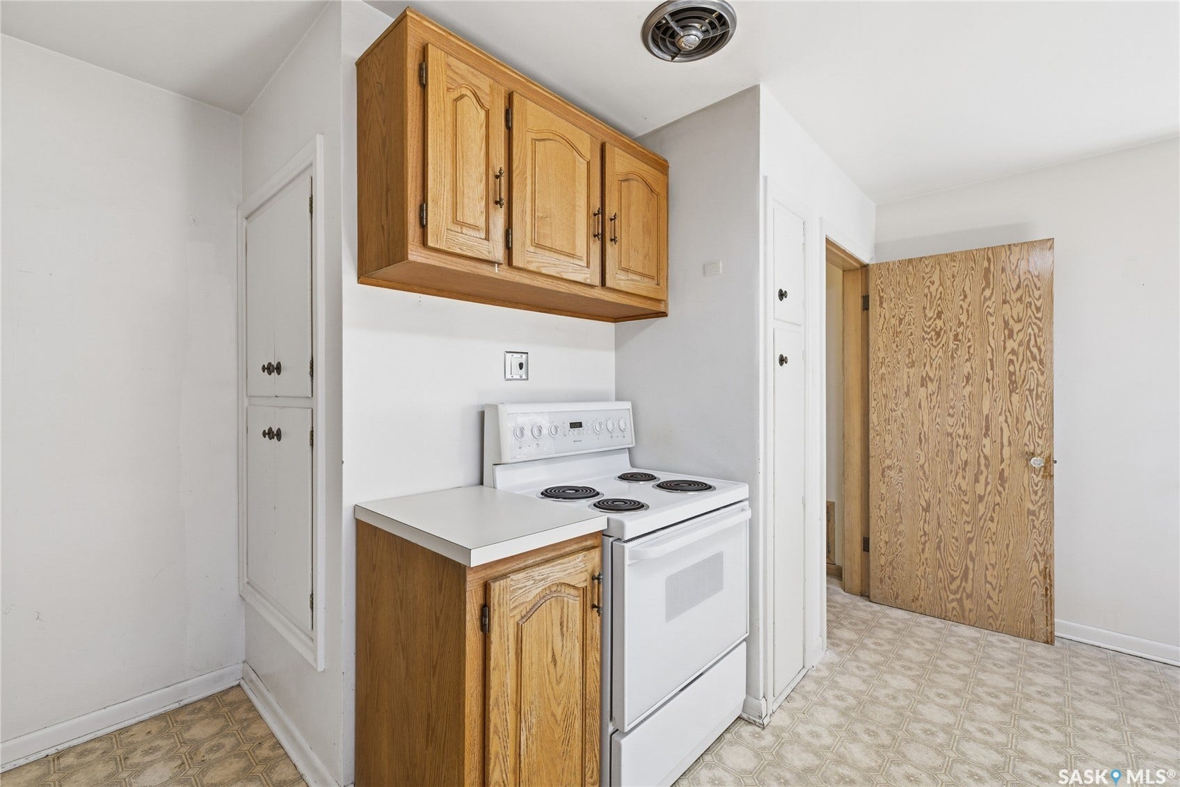 Wood-finish cabinetry paired with white countertops and a white electric range