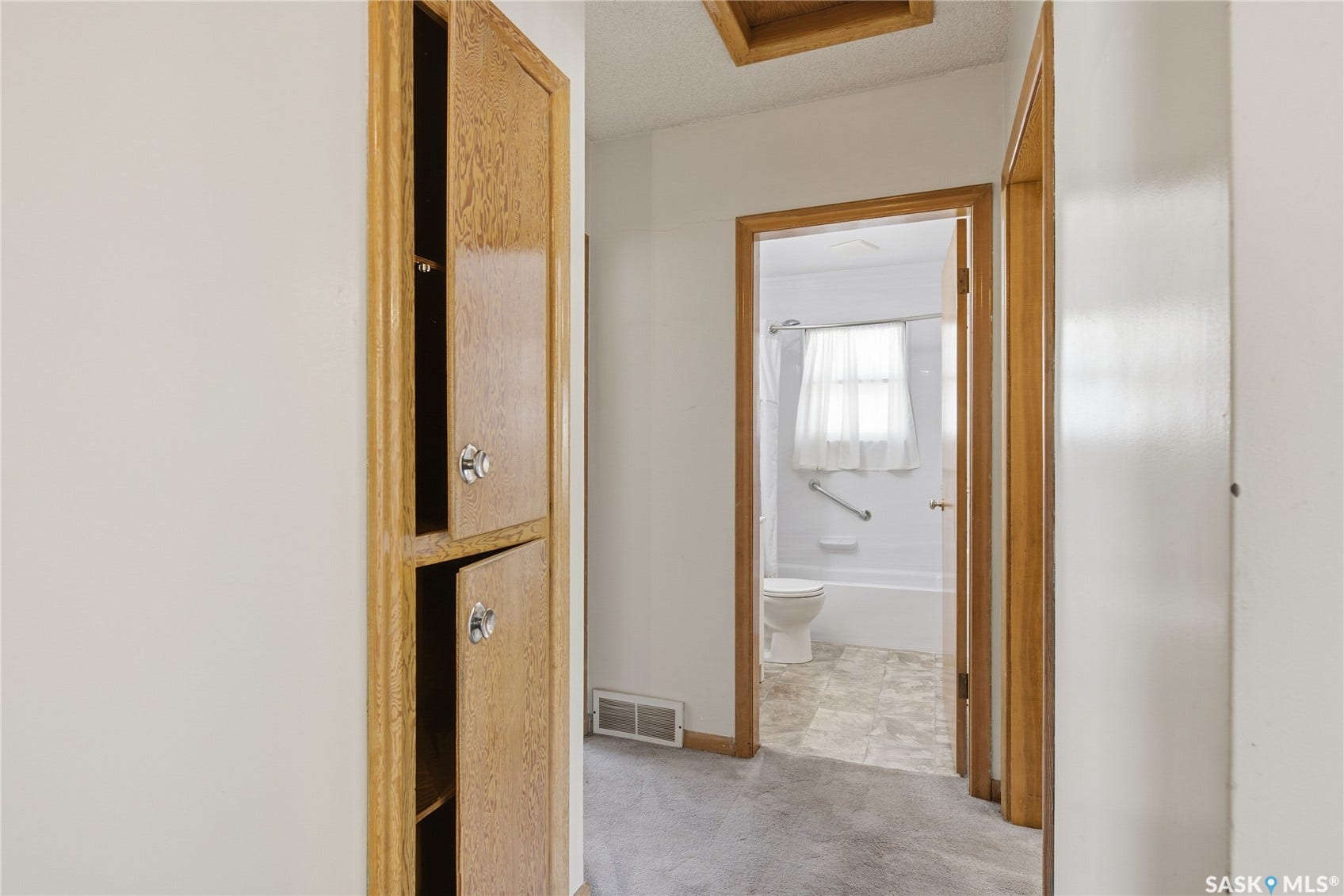 Built-in wood-finish cabinetry with decorative hardware, wood-finish trim, and light grey carpeting