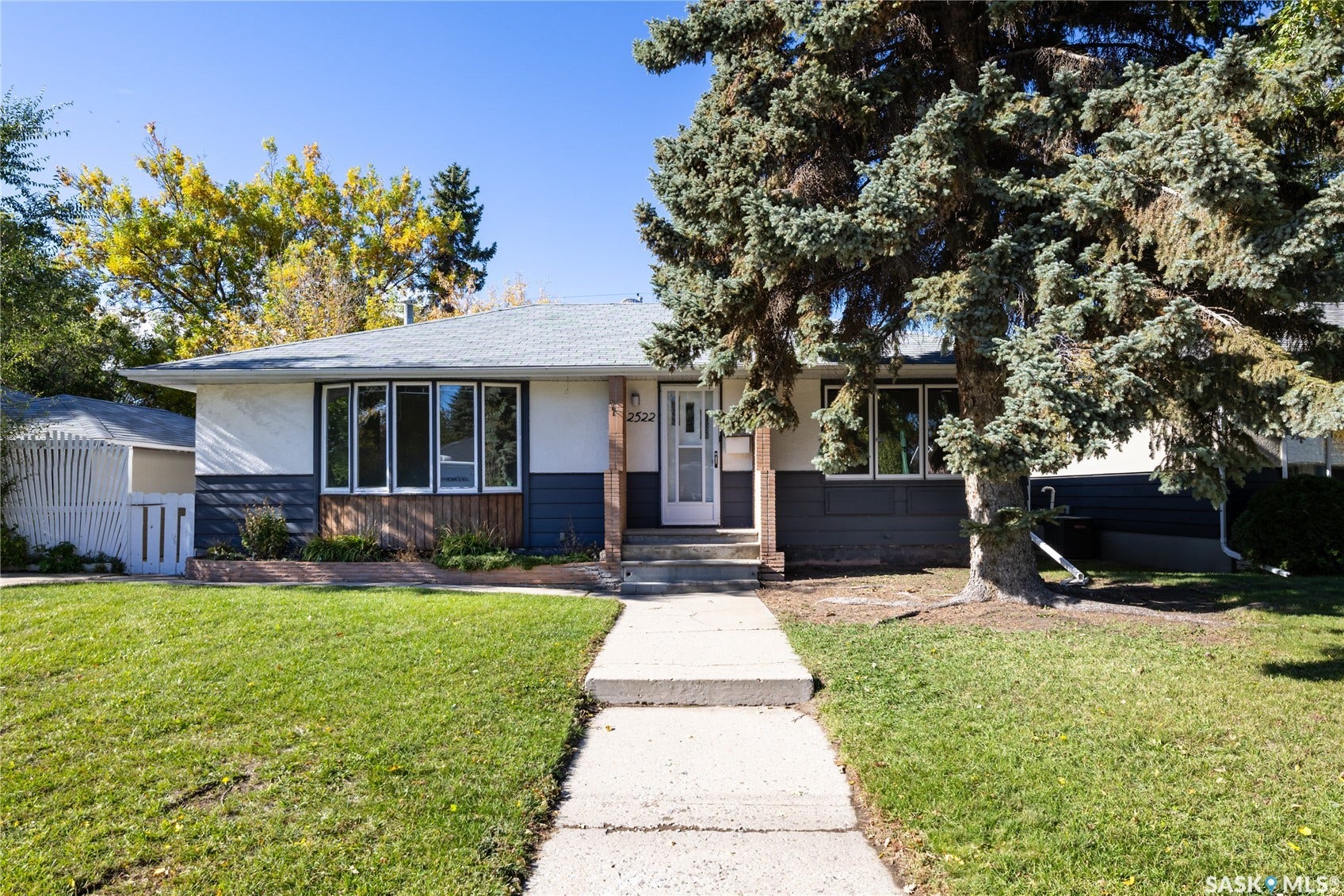 Contemporary exterior featuring multi-toned siding, a prominent bay window, and a concrete walkway