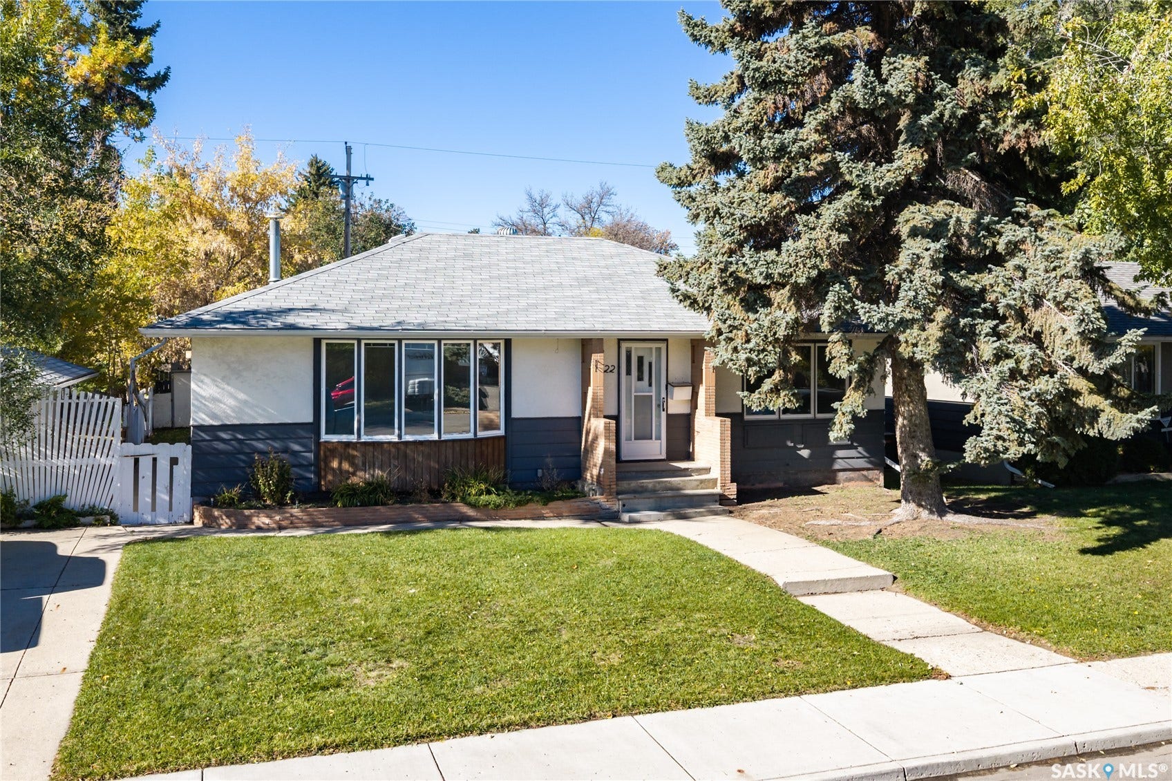 Single-story residence featuring a gray shingle roof, two-tone exterior siding, a front entry with a white storm door, and a bay window
