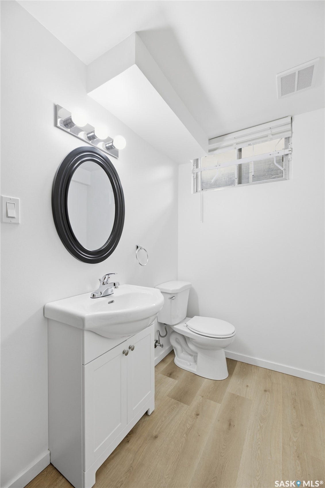 White pedestal vanity with integrated sink, chrome faucet, and oval wall mirror