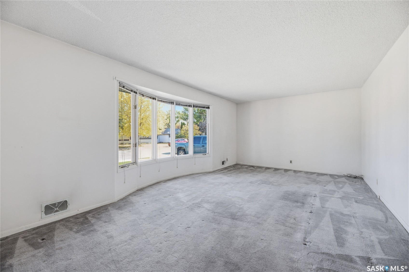 Spacious room featuring a curved bay window and light-colored walls
