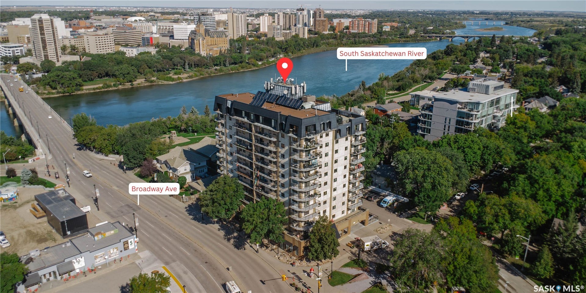 Multistory building with balconies, situated alongside a river and a prominent roadway