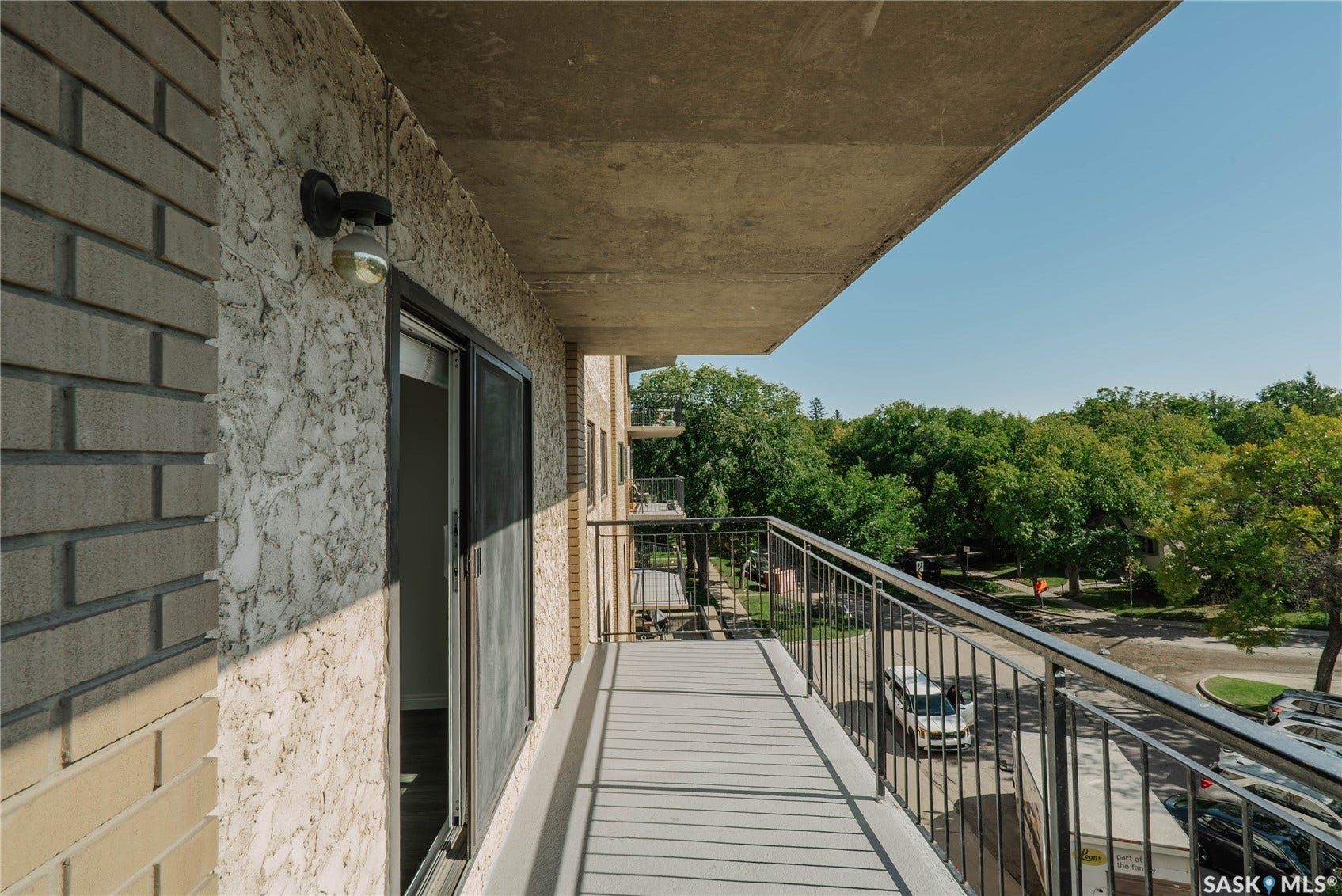 Exterior balcony featuring a concrete floor, metal railing, and sliding glass door access