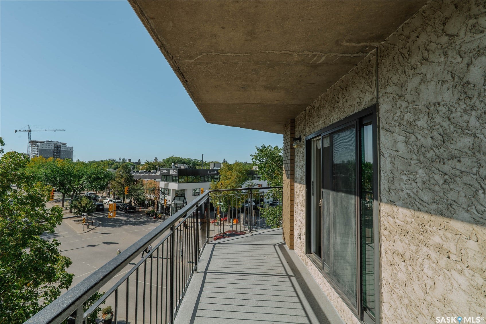 Balcony with metal railings and a sliding glass door, offering an urban streetscape