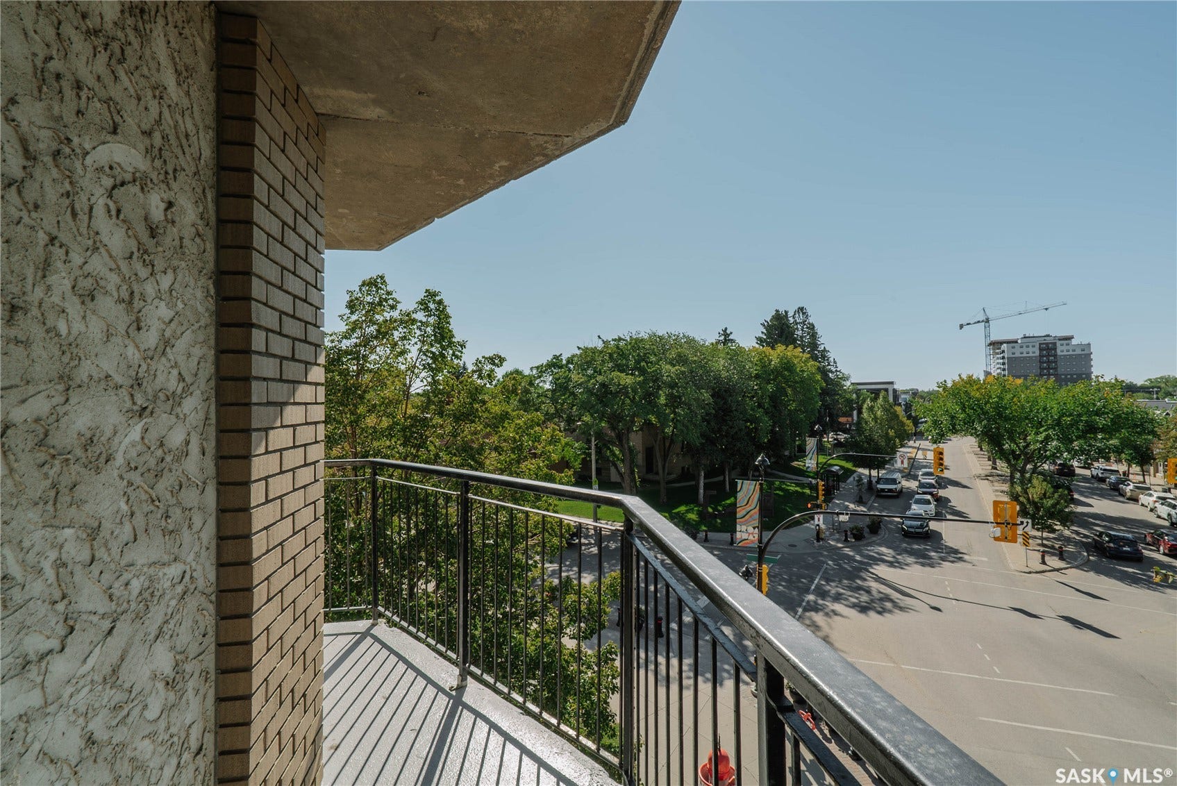 Balcony featuring a metal railing, concrete flooring, and an exterior brick wall