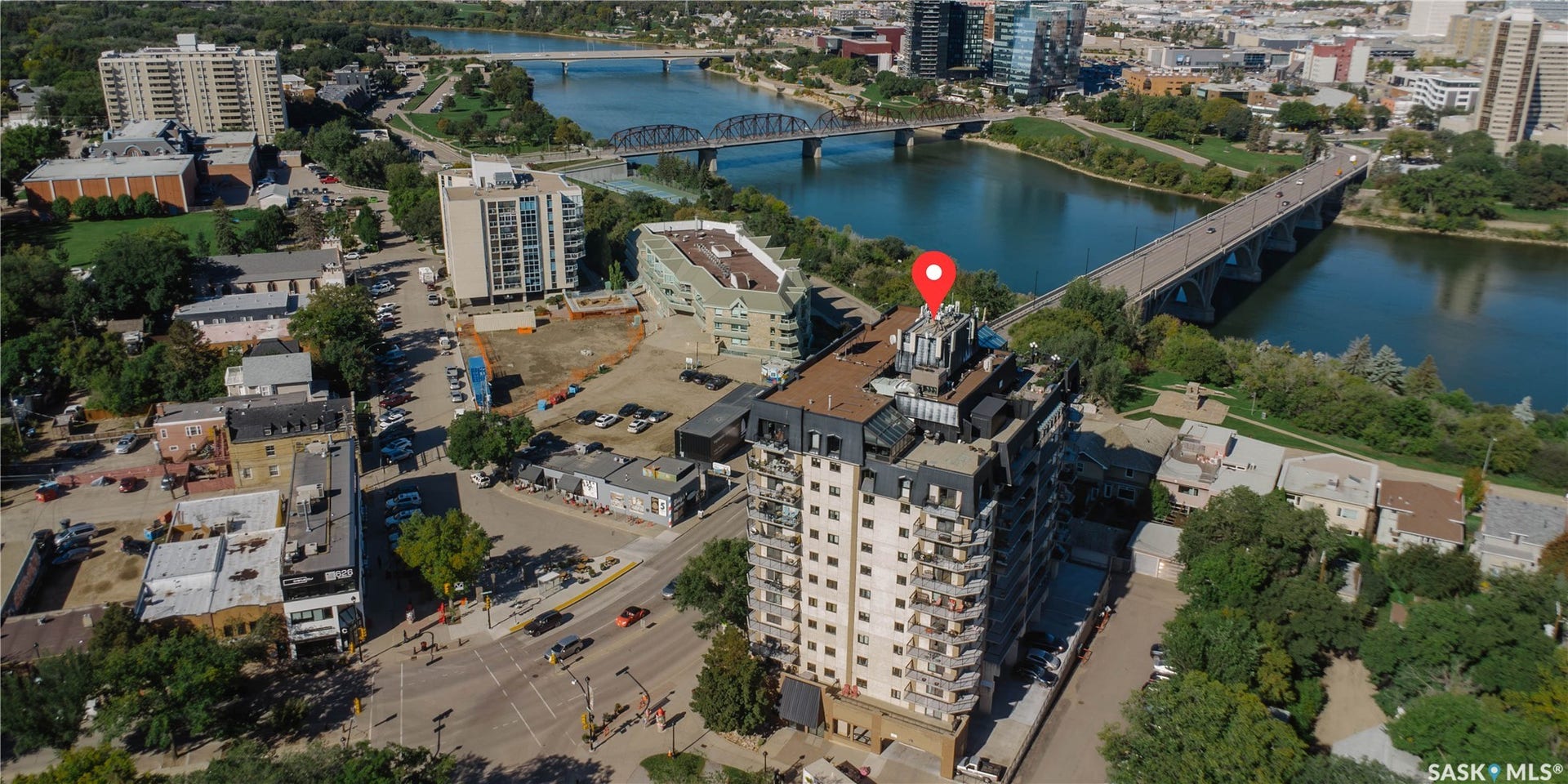 High-rise condominium building featuring multiple balconies, a flat roof, and an urban riverfront setting