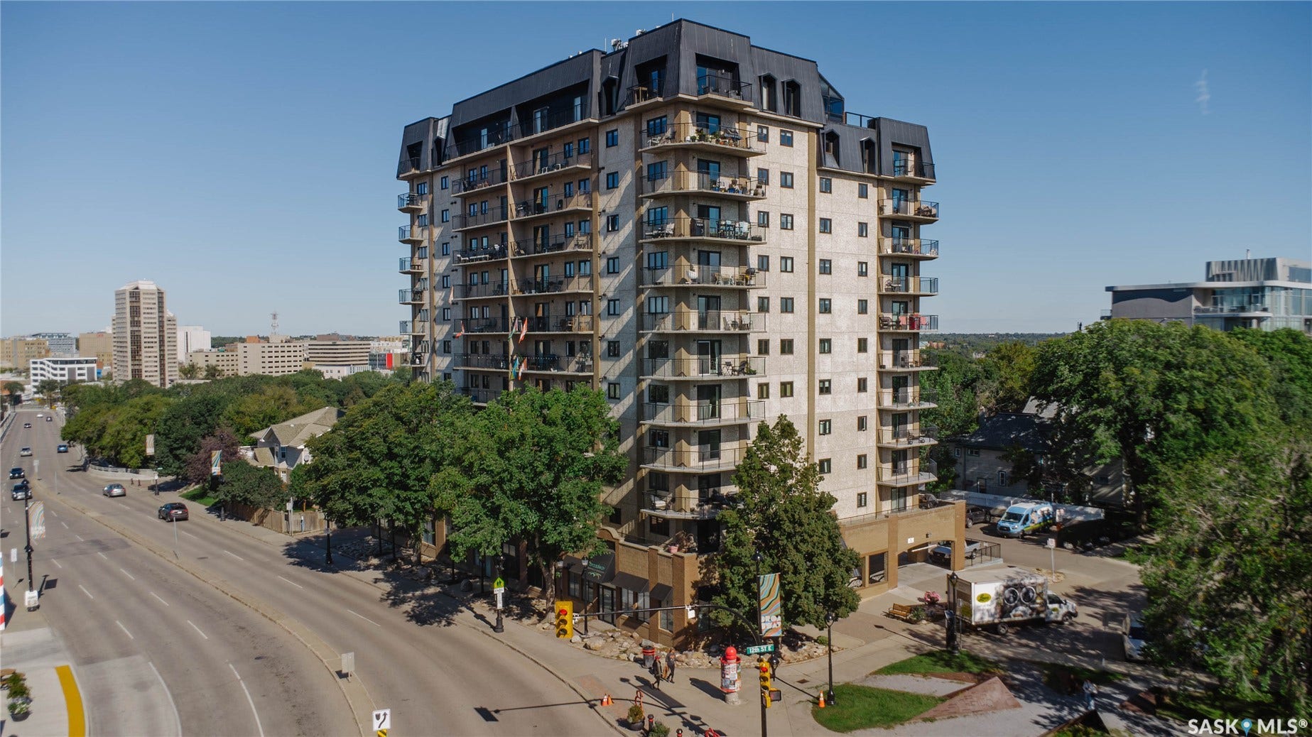 Multi-story building featuring numerous balconies and a distinctive mansard-style roof