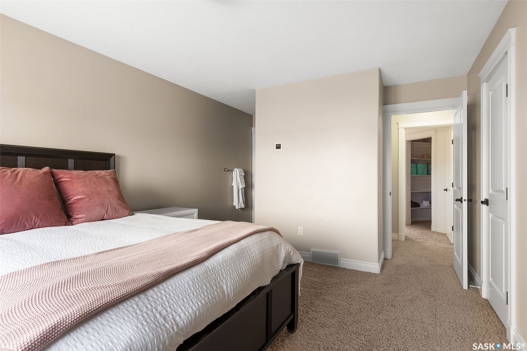 Neutral wall tones, plush carpet flooring, white trim, and white doors with dark hardware