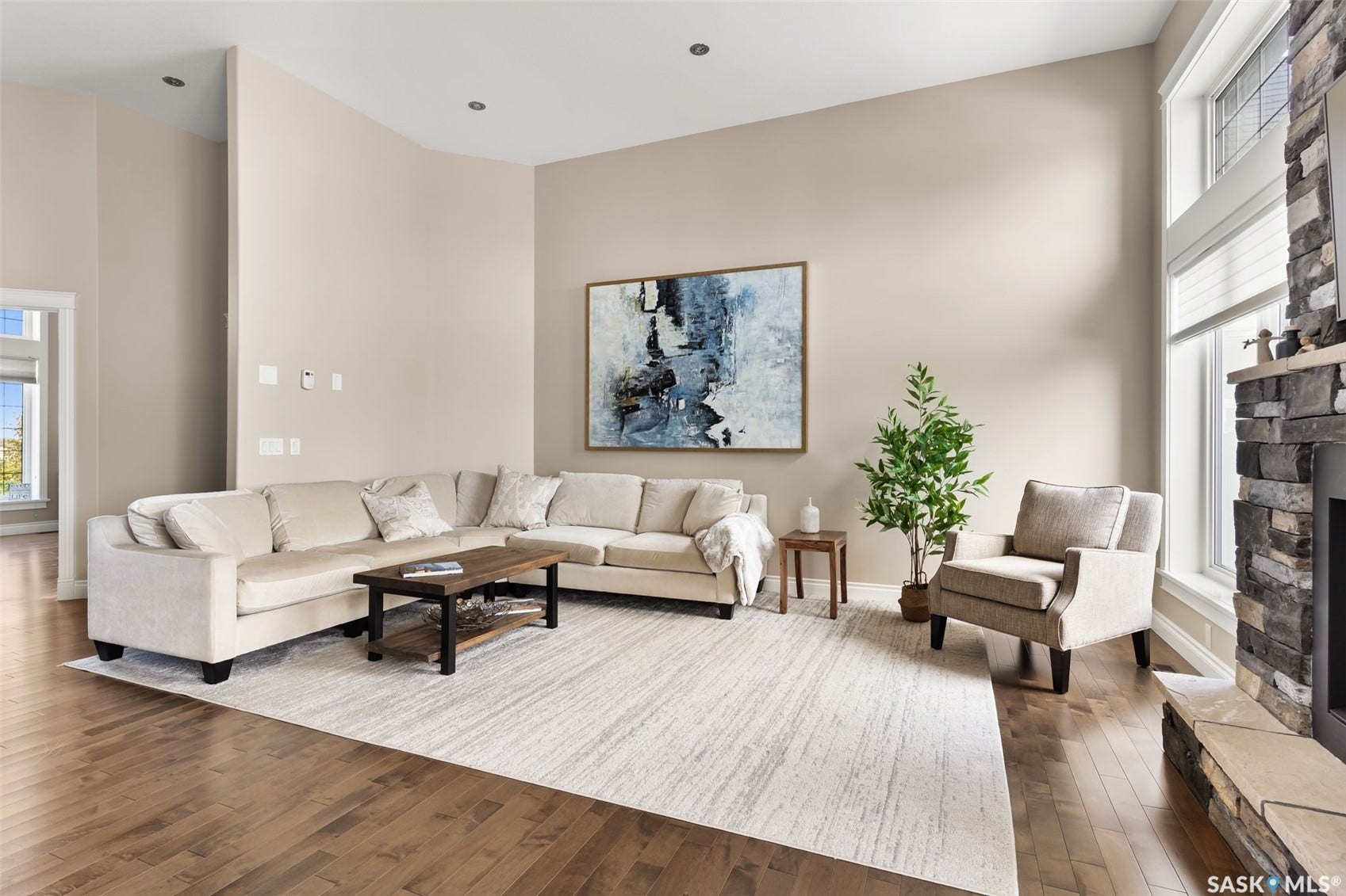 Hardwood-finish flooring, recessed lighting, and a stone-clad fireplace with a hearth