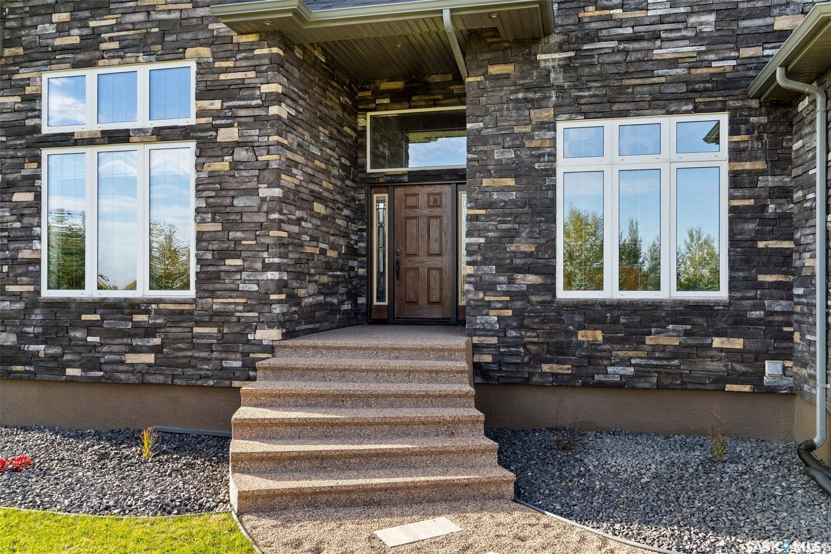 Stone exterior featuring multiple windows, a wood-finish entry door, and concrete steps