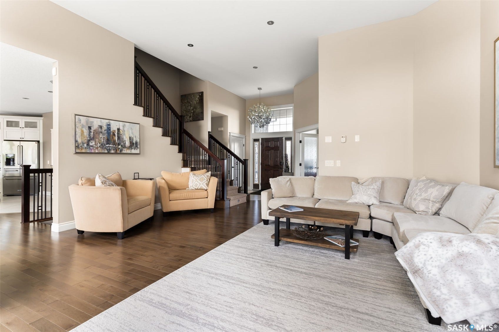 Hardwood flooring, dark wood staircase with balusters, recessed lighting, and a front entry with a chandelier